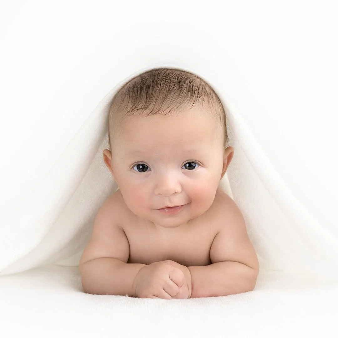 baby holding up his head with blanket