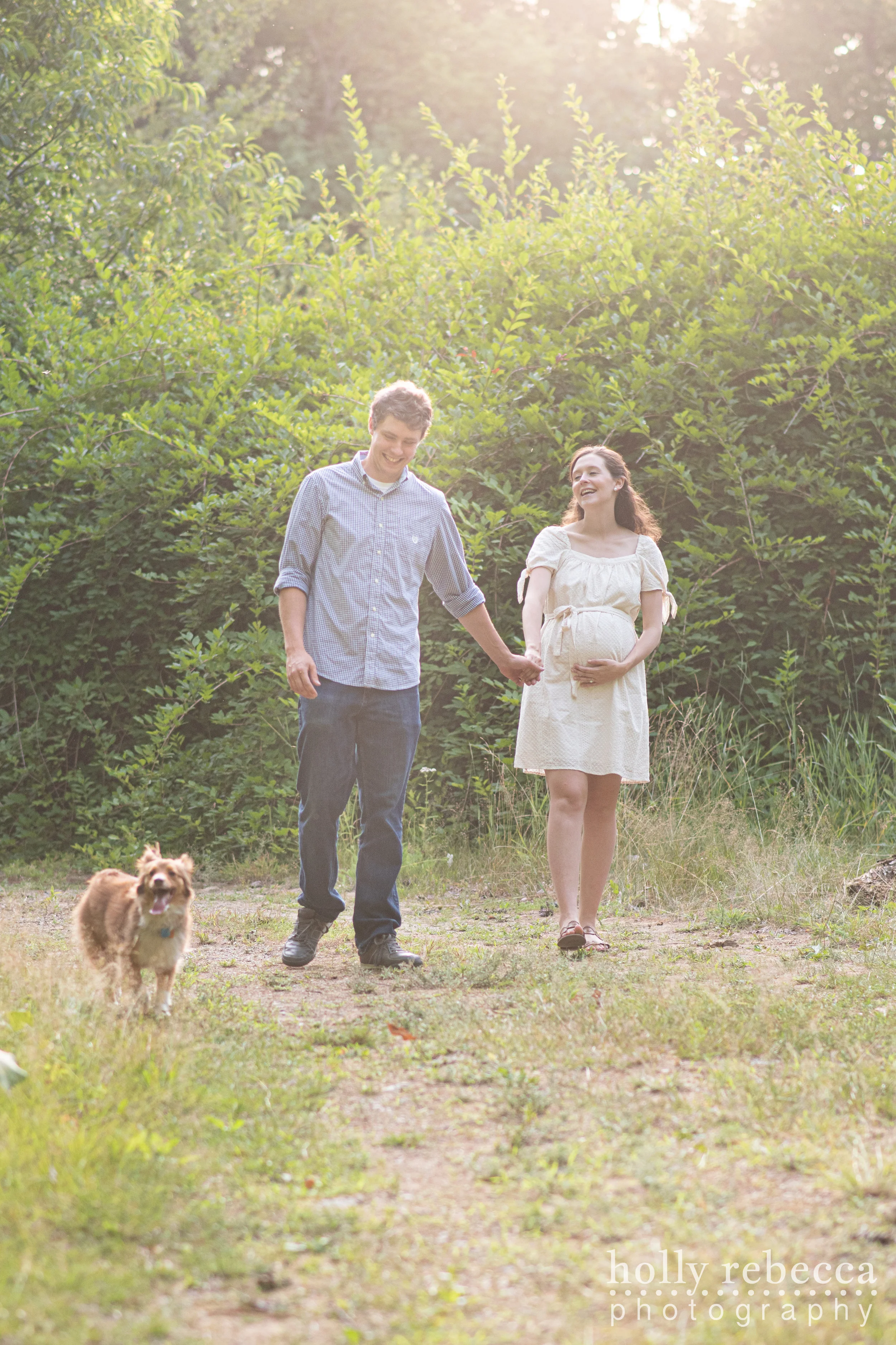 Happy pregnant couple walking with dog