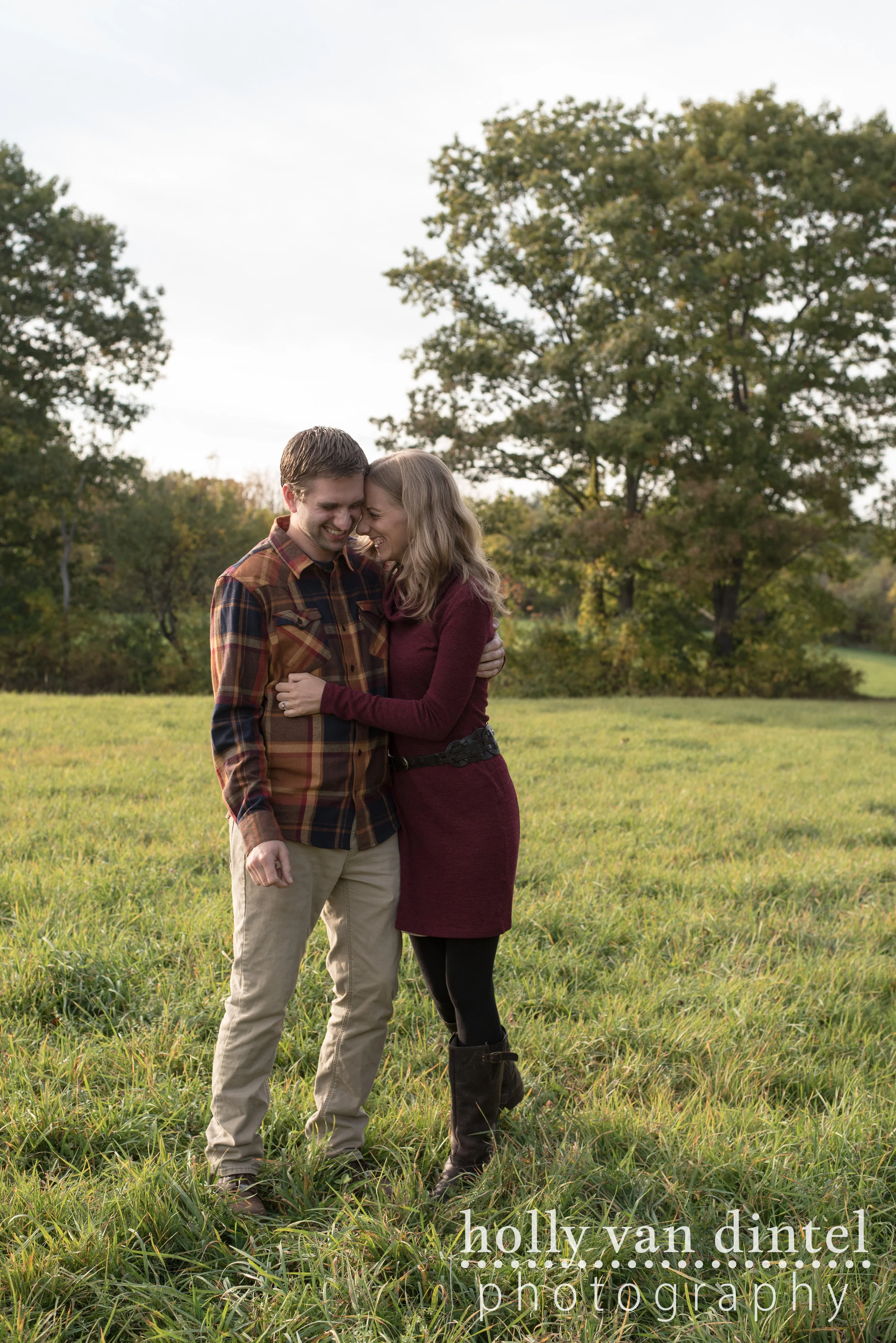 Engaged couple hugging in field