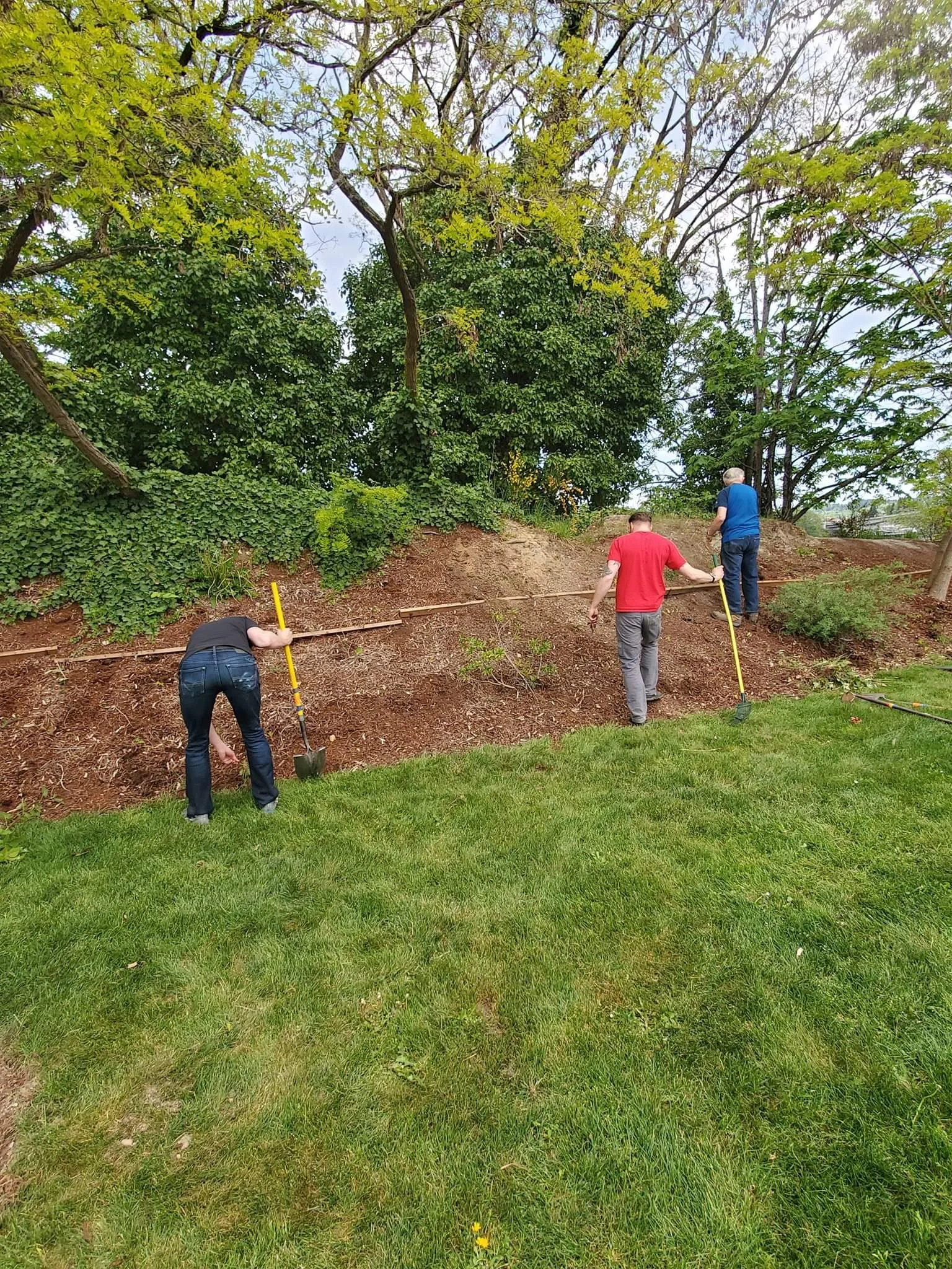 Volunteers clearing the bark around the memorial of any weeds and brush