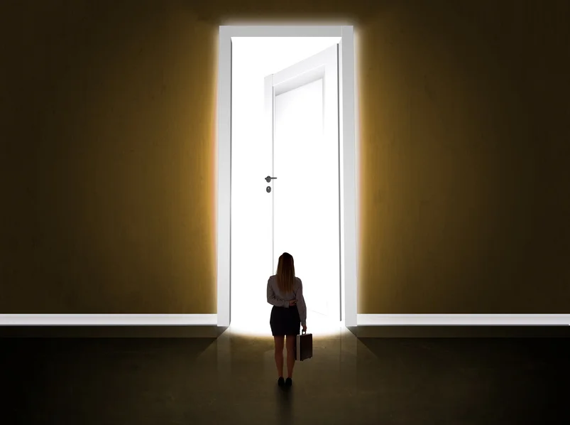 Business woman looking at big bright opened door