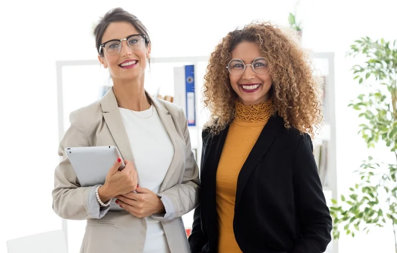 Two beautiful young businesswoman posing in the office.