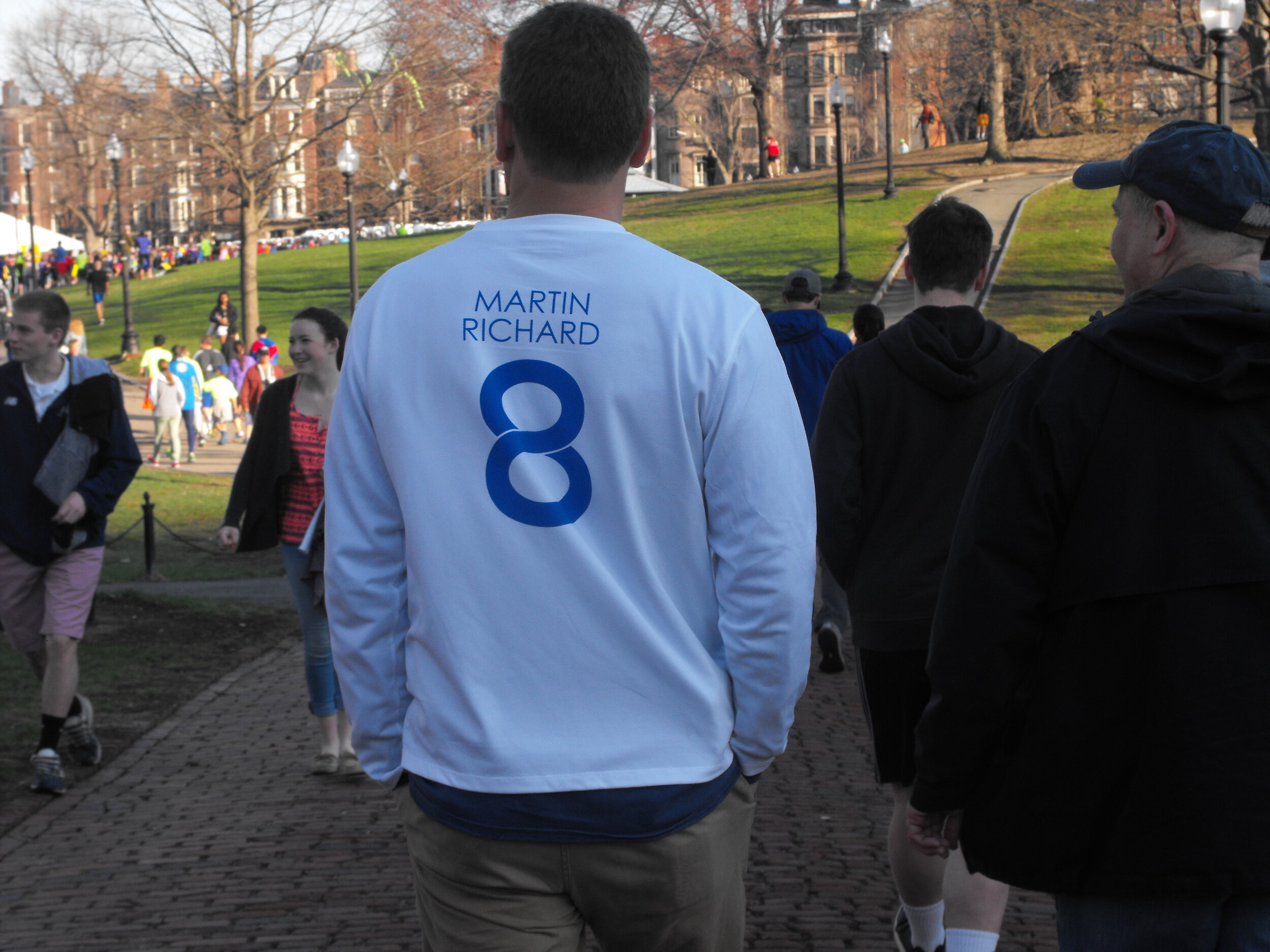  Boston. April 18, 2015. As over 10,000 registered 5k participants quickly make their way towards the starting line, a man dons his Martin Richard 8 shirt, paying tribute to the eight-year-old young boy who tragically died in the 2013 marathon bombin