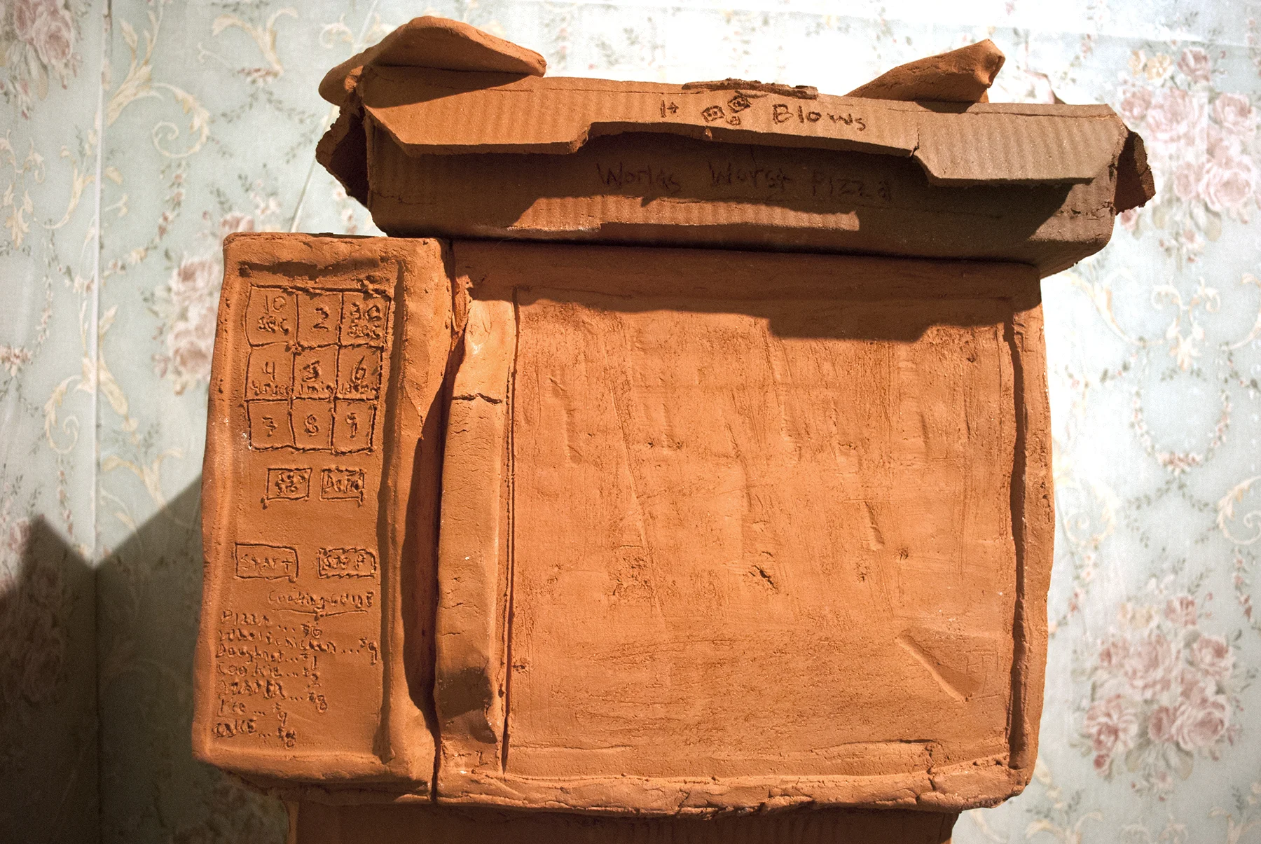 Terracotta, slip cast porcelain, found unfired cheese burger, carpet, metal, found cabinet, wallpaper, drywall, wood, latex Installation of life sized objects in 6’x12’x8’ room. 2018