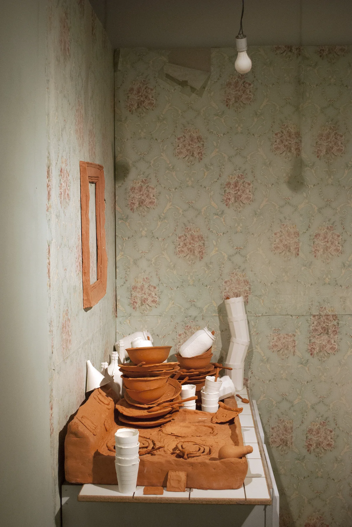Terracotta, slip cast porcelain, found unfired cheese burger, carpet, metal, found cabinet, wallpaper, drywall, wood, latex Installation of life sized objects in 6’x12’x8’ room. 2018