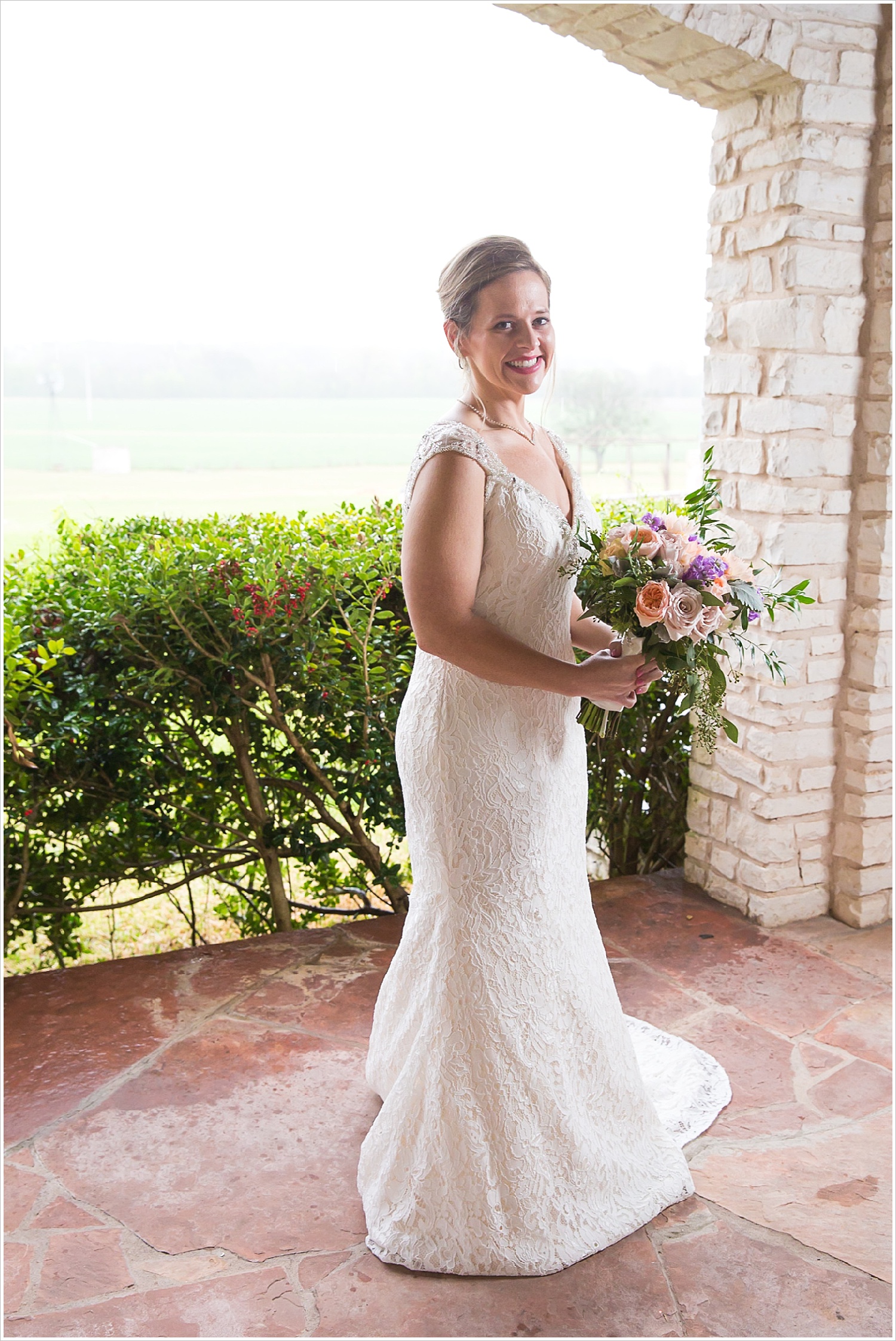 Bride stands under covered porch during rain storm at La Rio Mansion
