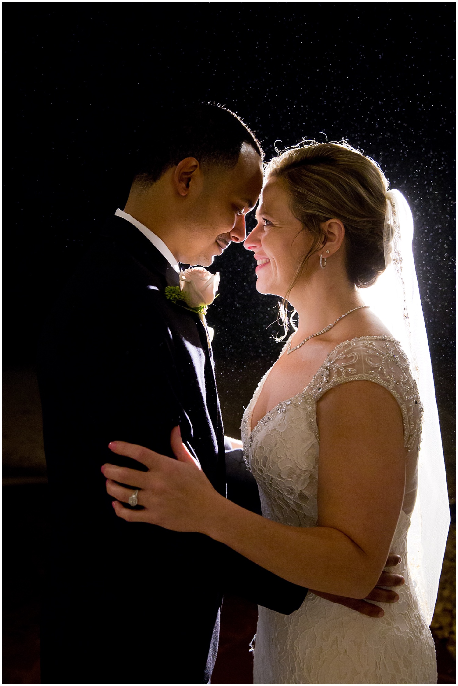 Bride and groom look lovingly into each other's eyes during rainstorm on their wedding day