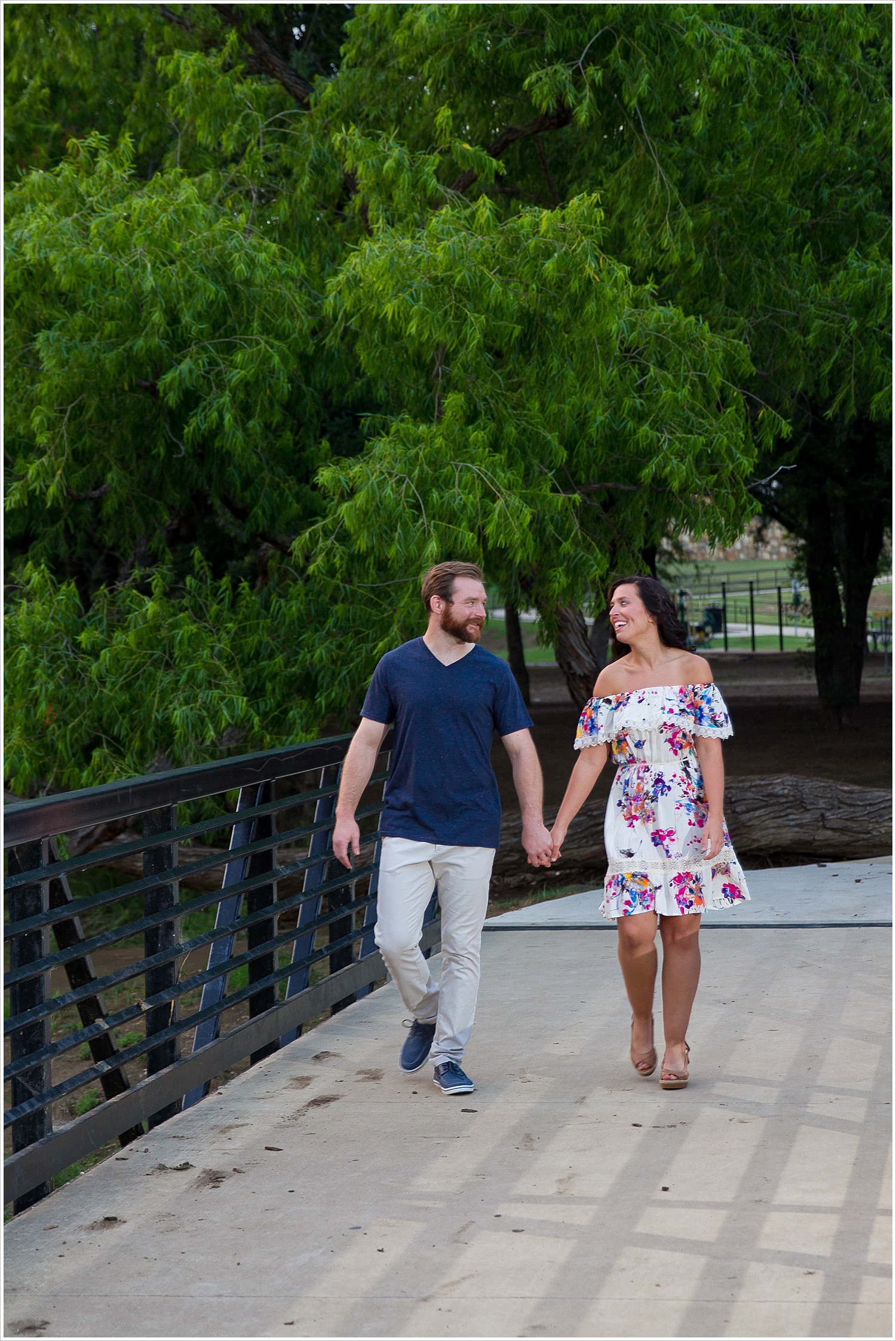 Randell & Fawn stand on a bridge in the park where Randell proposed at an engagement photography session in Frisco, Texas by Texas wedding photographers Jason & Melaina Photography, www.jasonandmelaina.com
