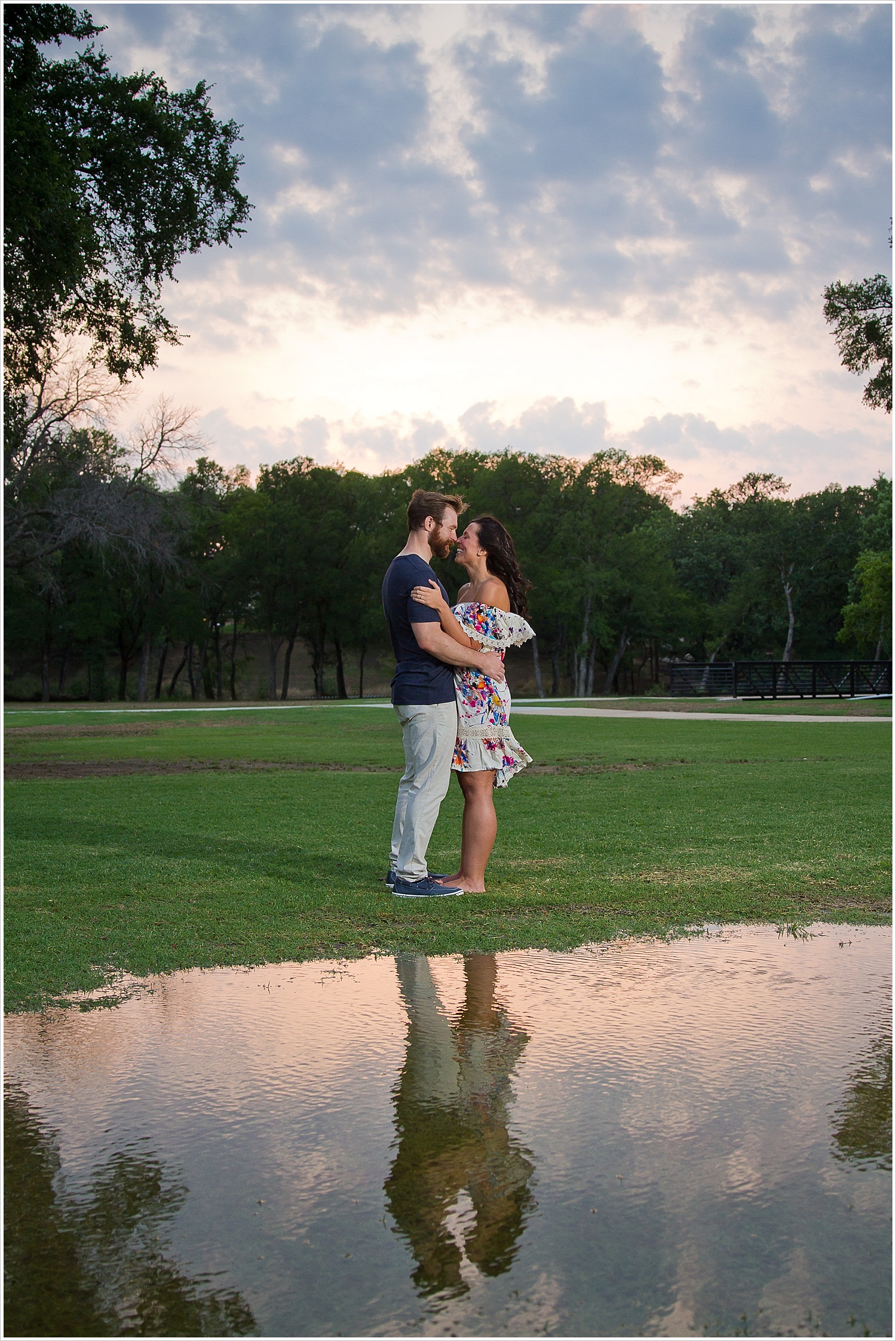 Randell & Fawn embrace with a Texas sunset sky in the background at an engagement photography session in Frisco, Texas by Texas wedding photographers Jason & Melaina Photography, www.jasonandmelaina.com