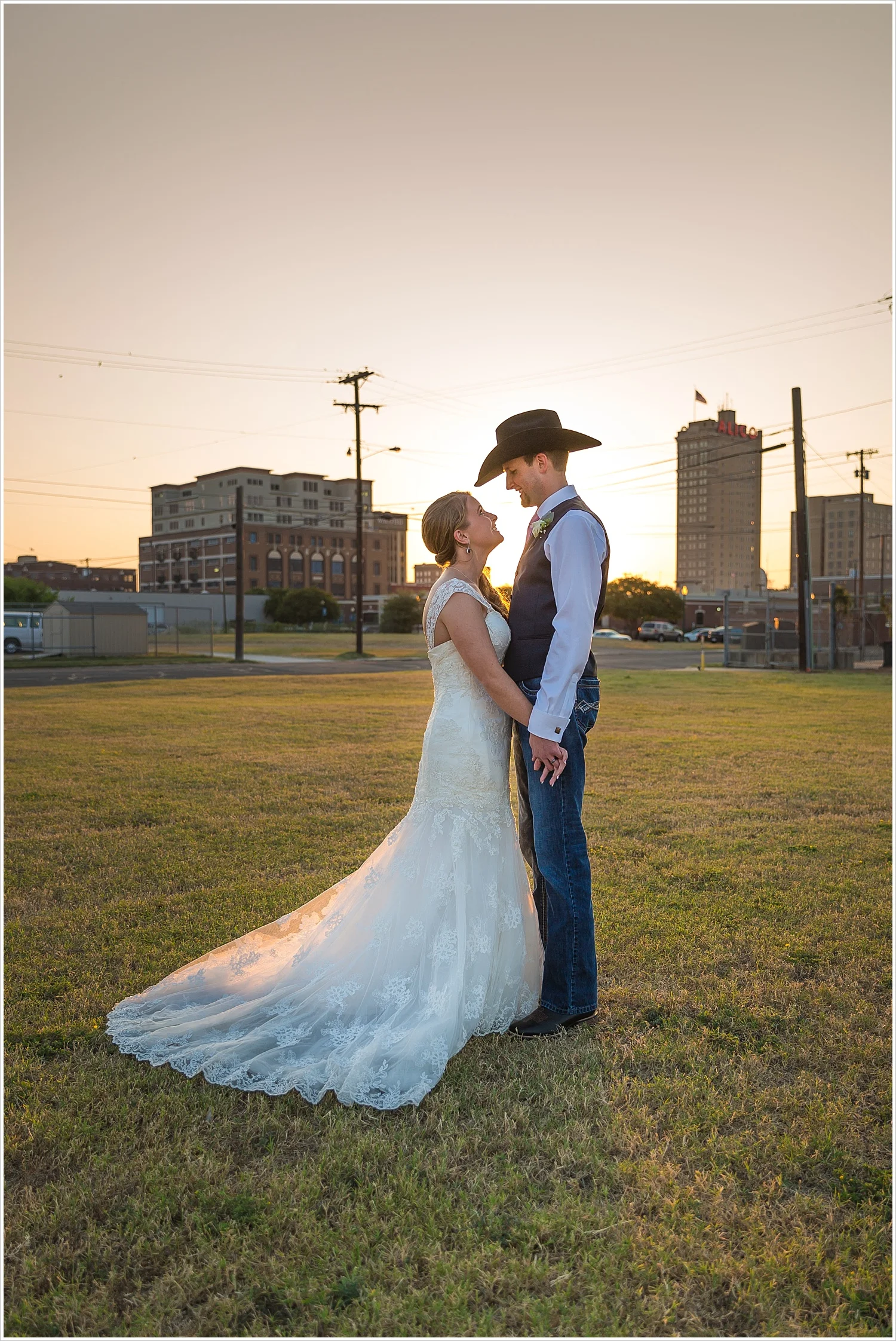Bride and groom stand together with Waco skyline and sunset behind them, Navy and blush Texas Reception at The Phoenix Ballroom, Jason & Melaina Photography - www.jasonandmelaina.com