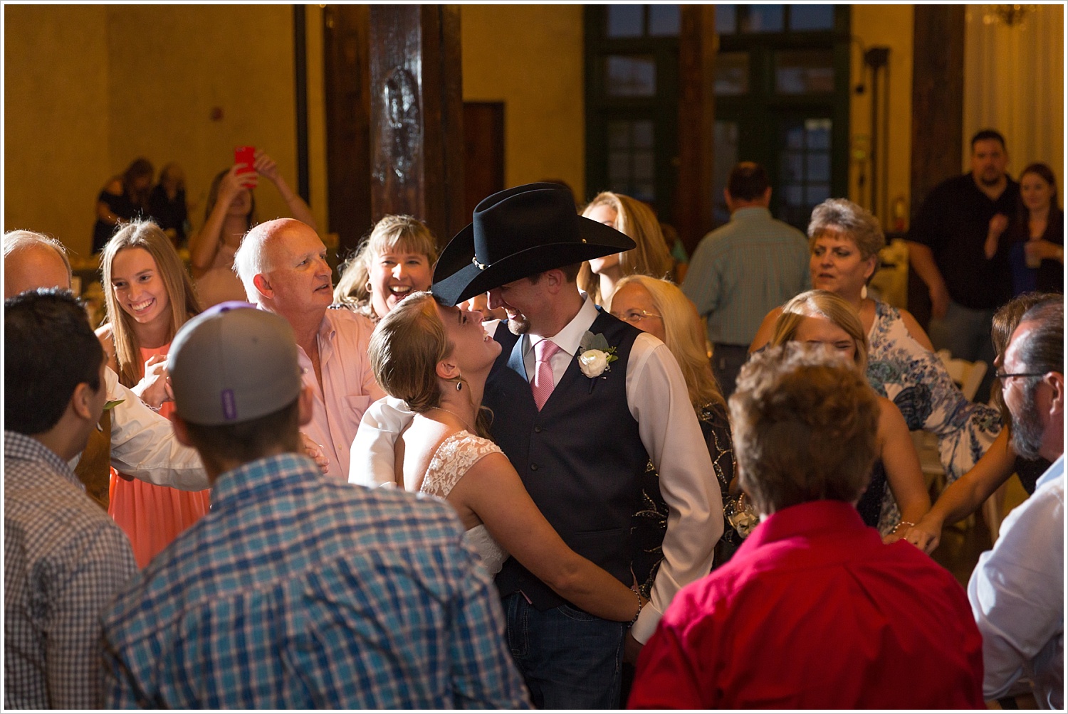 Bride and groom laugh during first dance as their family dances around them, Navy and blush Texas Reception at The Phoenix Ballroom, Jason & Melaina Photography - www.jasonandmelaina.com