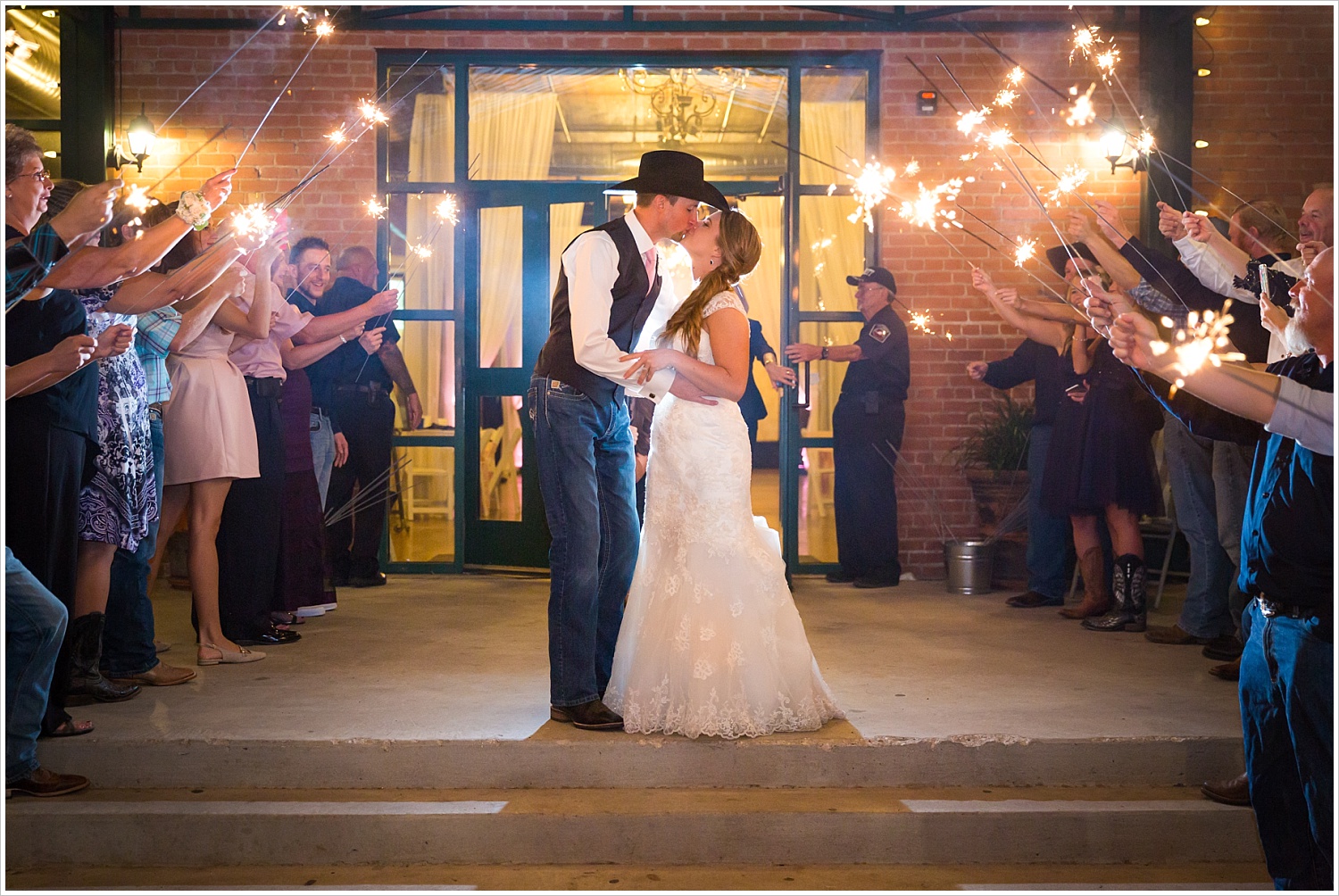 Bride and groom kiss during sparkler exit outside The Phoenix in Waco, Navy and blush Texas Reception at The Phoenix Ballroom, Jason & Melaina Photography - www.jasonandmelaina.com