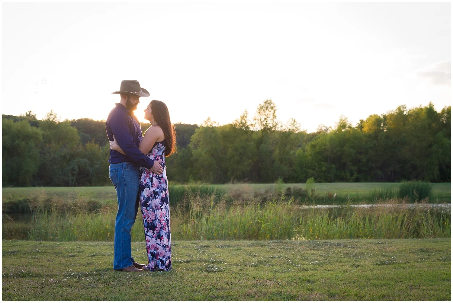 A couple holds one another with Texas sunset behind their faces during their engagement photo session in Waco, Texas, Jason & Melaina Photography - www.jasonandmelaina.com