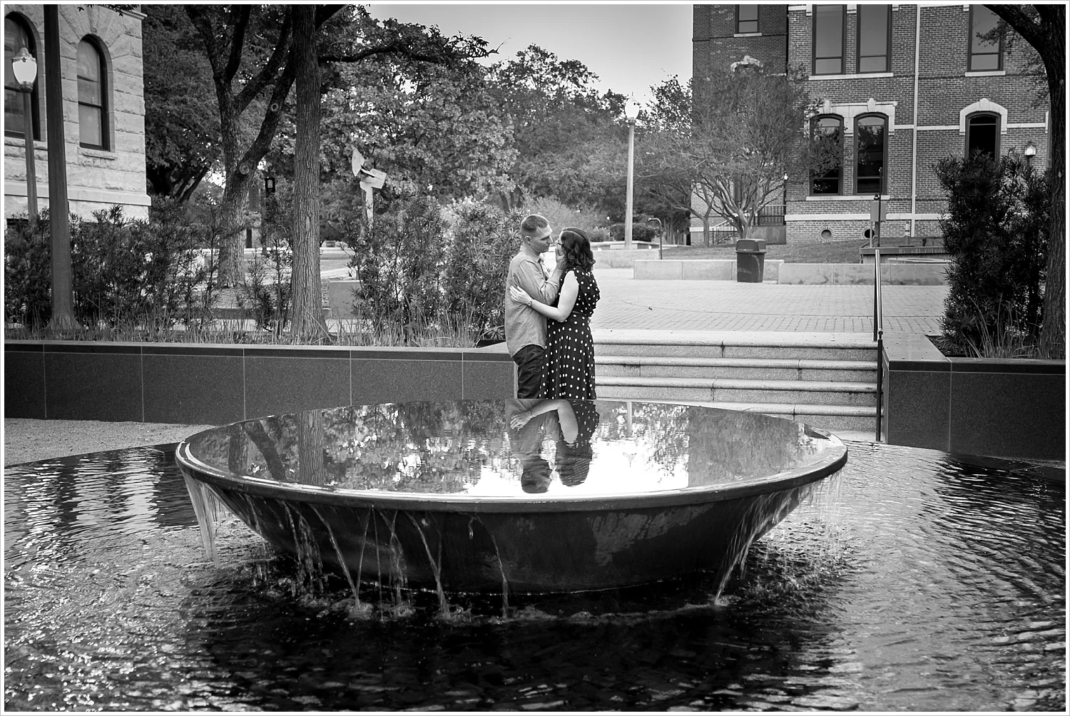Couple embraces behind reflective fountain on Baylor University's campus - Jason & Melaina Photography - www.jasonandmelaina.com
