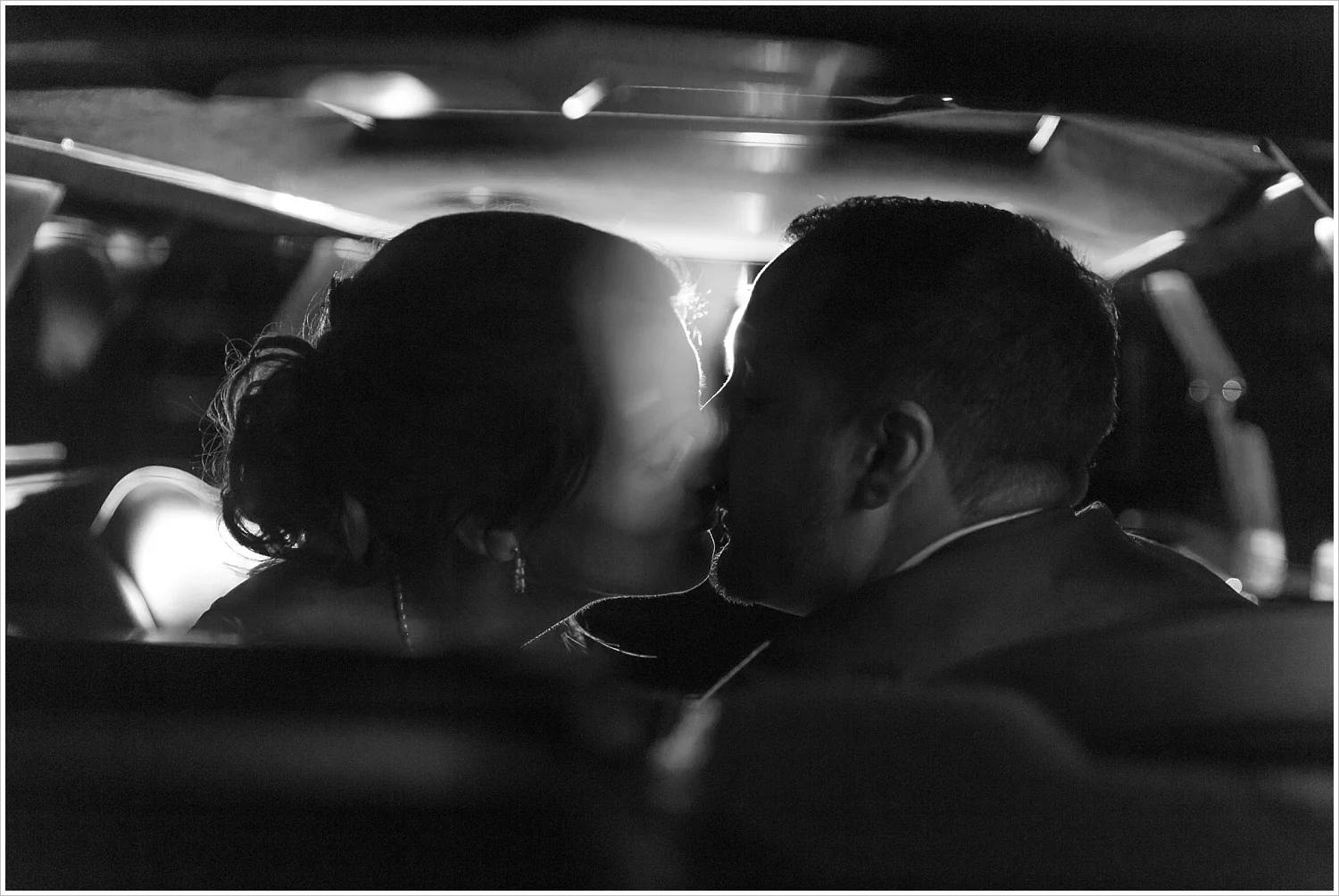 Groom and bride kiss in the back of their limo as they leave their wedding reception - Jason & Melaina Photography - www.jasonandmelaina.com
