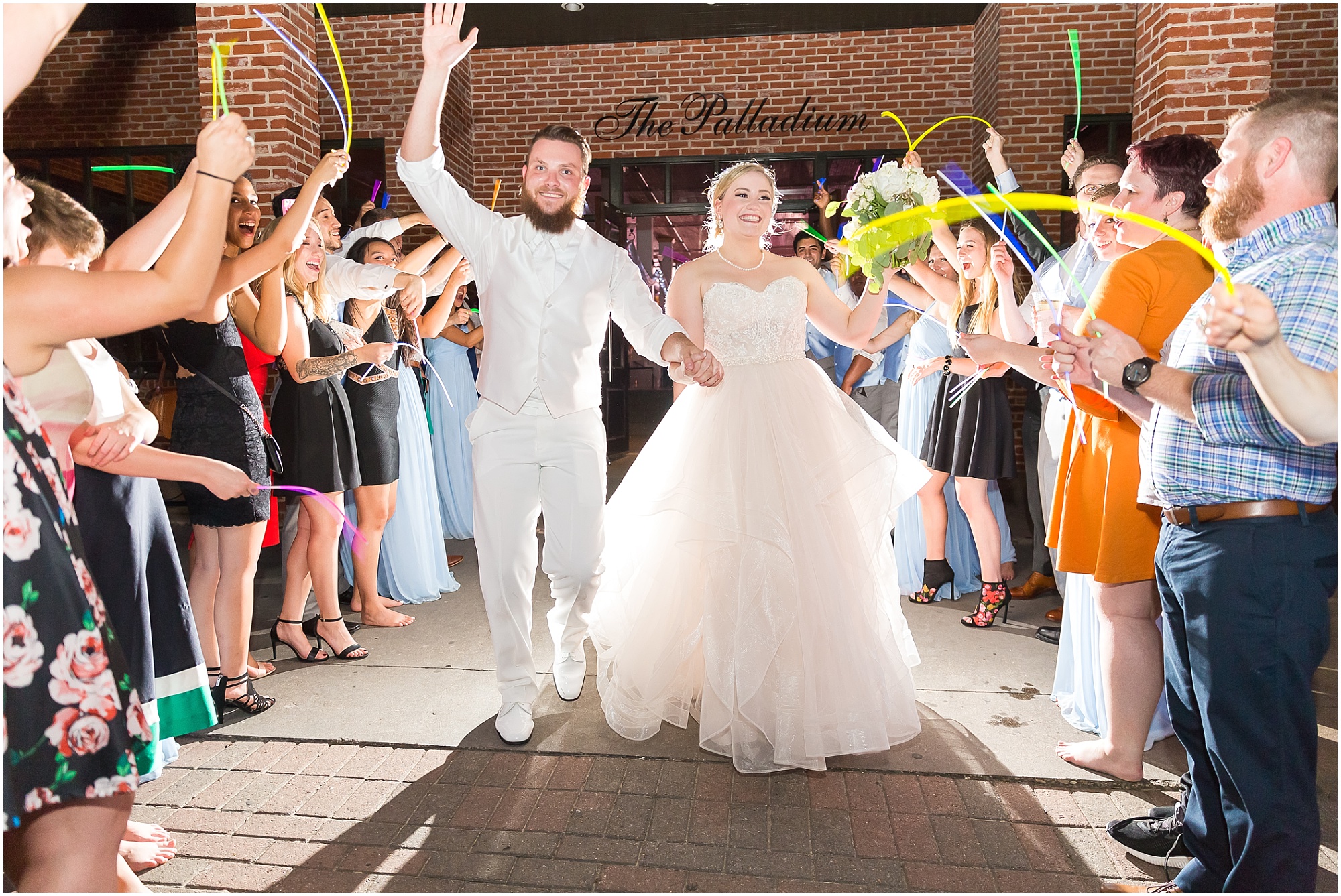 A bride & groom leave their warehouse reception at The Palladium while guests wave glow sticks, Downtown Waco Texas - www.jasonandmelaina.com