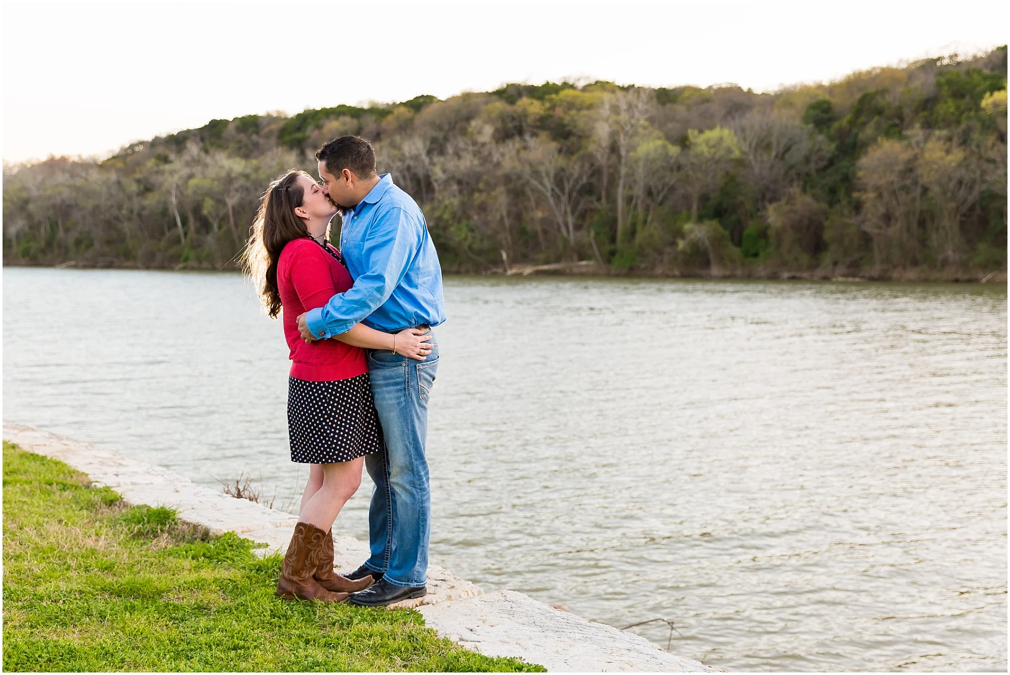 A boy and girl kiss alongside the river and cliffs in Brazos Park East in Waco, Texas during their engagement photo session - Jason & Melaina Photography - www.jasonandmelaina.com