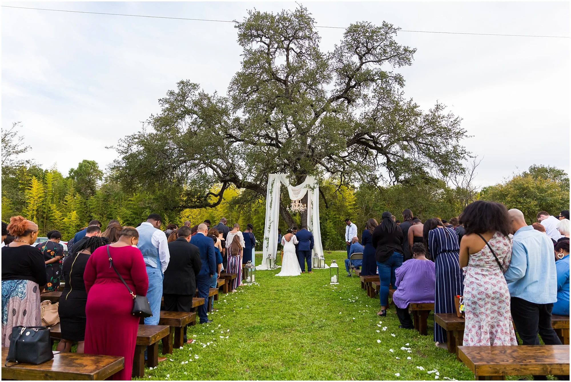 A bride and groom stand under a large oak tree during their wedding ceremony at Lover’s Leap in Cameron Park, Waco, Texas - Jason & Melaina Photography - www.jasonandmelaina.com