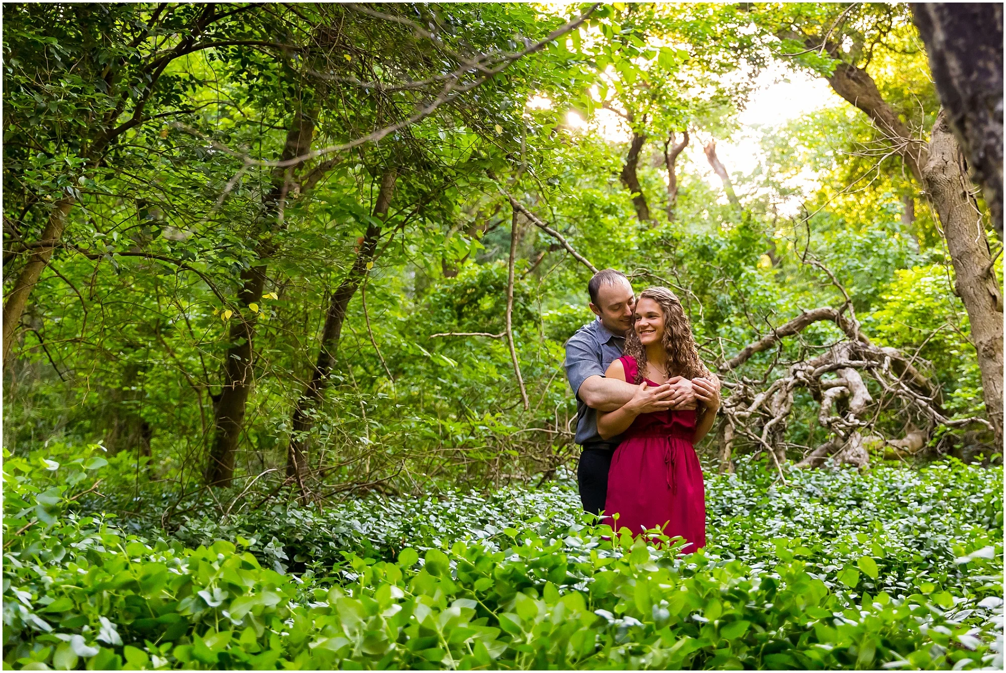 A man hugs his fiance from behind in a wooded trail inside Cameron Park in Waco, Texas - Jason & Melaina Photography - www.jasonandmelaina.com