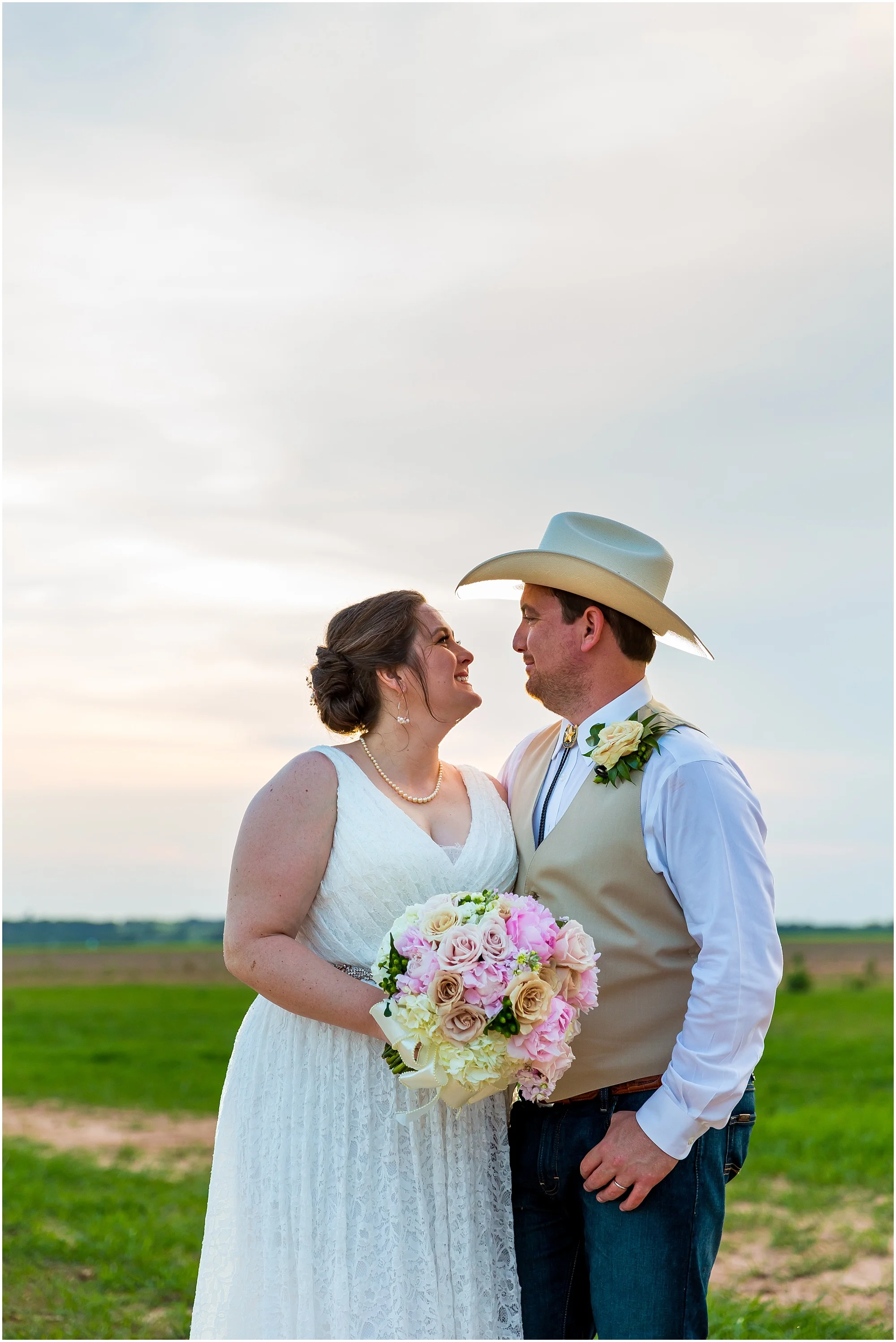 A bride and groom smile at one another with an expansive Texas sky behind them on their wedding day at Moon River Ranch | Jason & Melaina Photography | www.jasonandmelaina.com