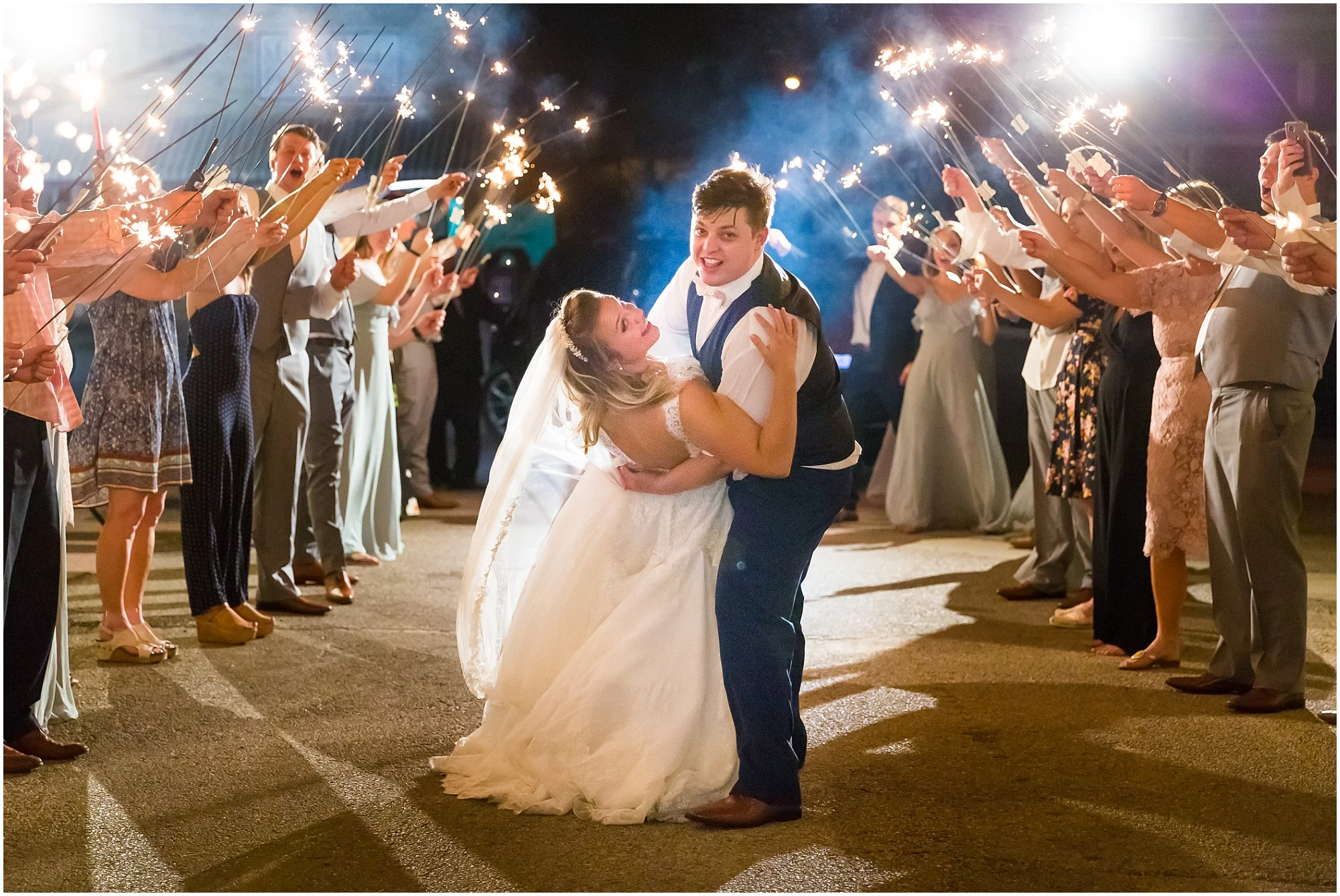 A groom dips his bride as they walk down a tunnel of sparklers as they leave their wedding - Jason & Melaina Photography - www.jasonandmelaina.com