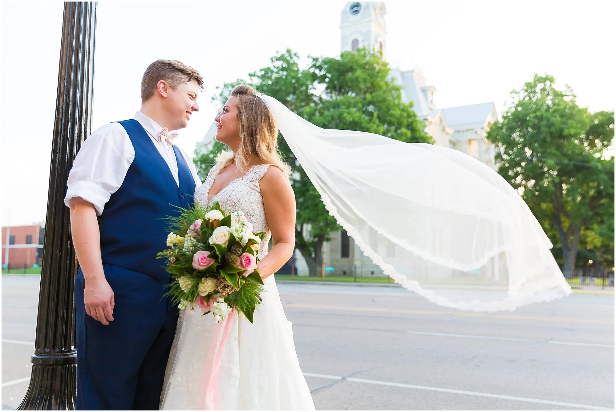 A bride smiles up at her groom while her veil floats in the wind - Jason & Melaina Photography - www.jasonandmelaina.com