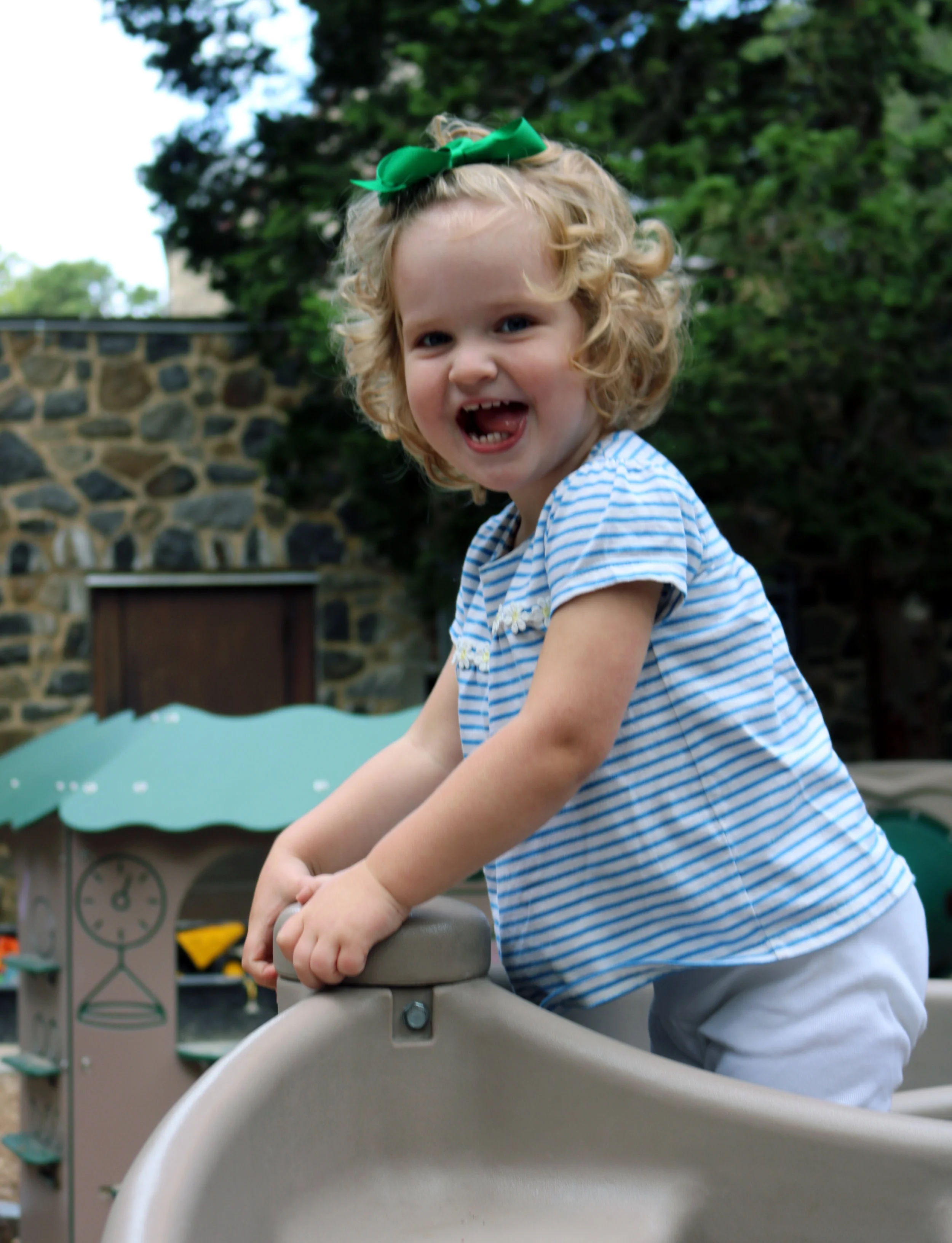 Joyful toddler girl climbing on playground equipment