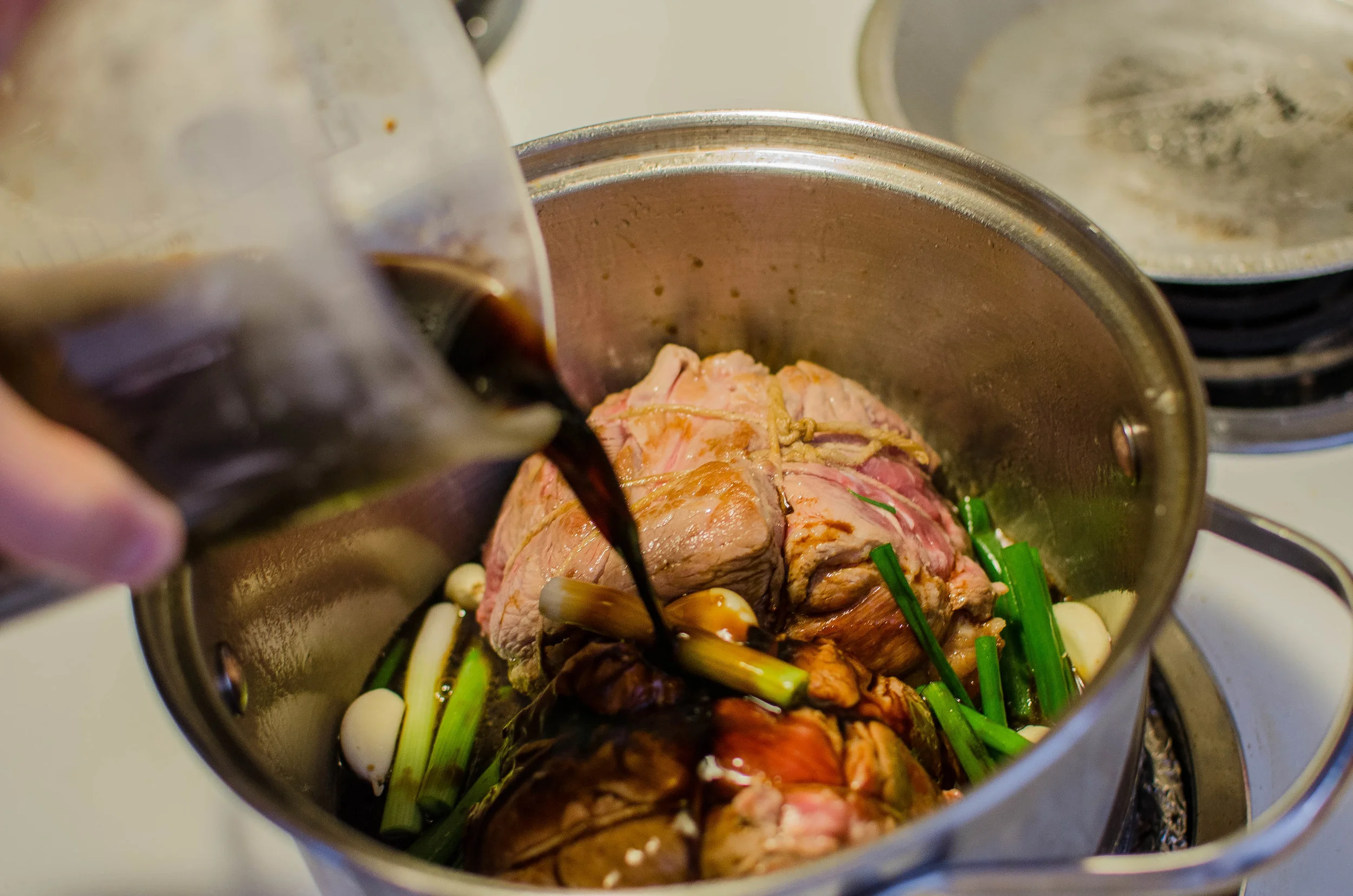 adding the marinade to the garlic, green onions, and meat.