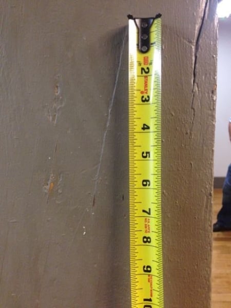 Photo shows painted timber with a depression in the coating that revealed a 1:6 slope of grain as a result of a split. The large split to the right of the ruler was the initial indicator for the presence of slope of grain. Rockefeller Hall. Cornell University, Ithaca, NY.