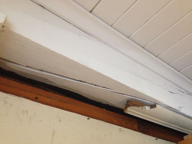 Timber with a large split revealing steep slope of grain. As a result this timber has partially failed in-situ.