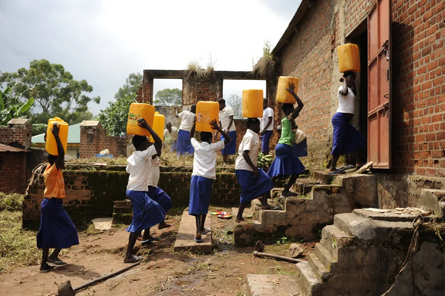 Students coming from the infectious Adhu river with water in jerry cans to bathe, cook, clean and drink with.