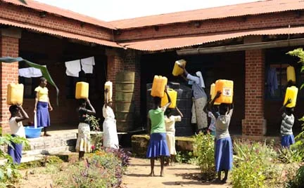 Luma students returning from fetching water from Adhu river 