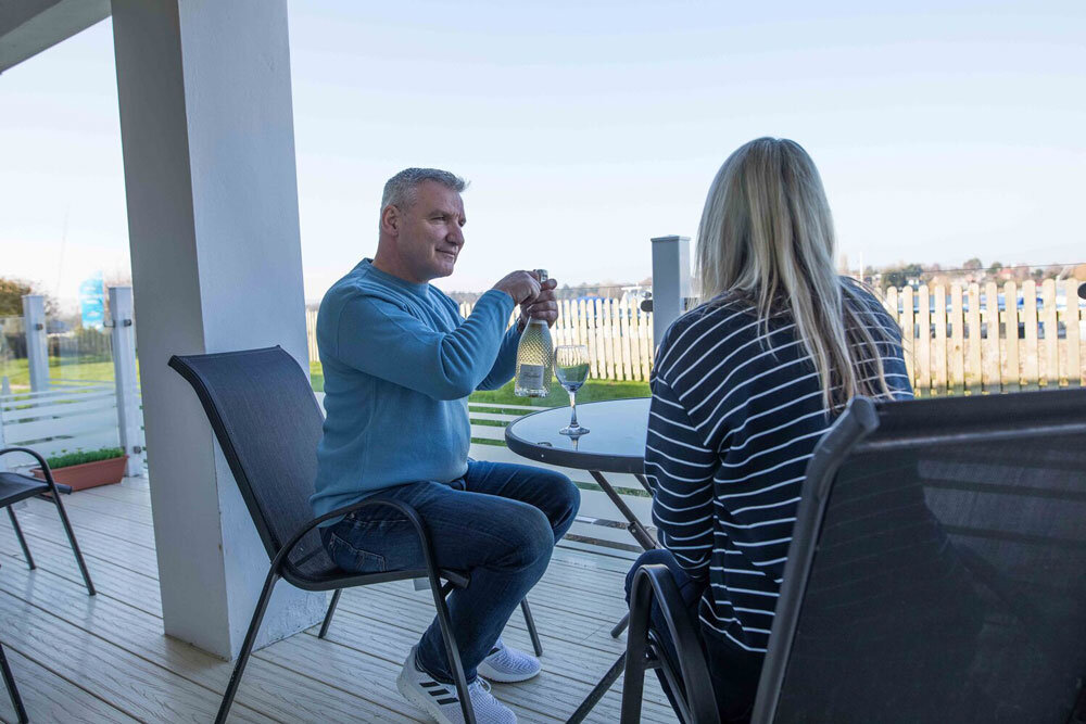 Couple on decking of brick built holiday home