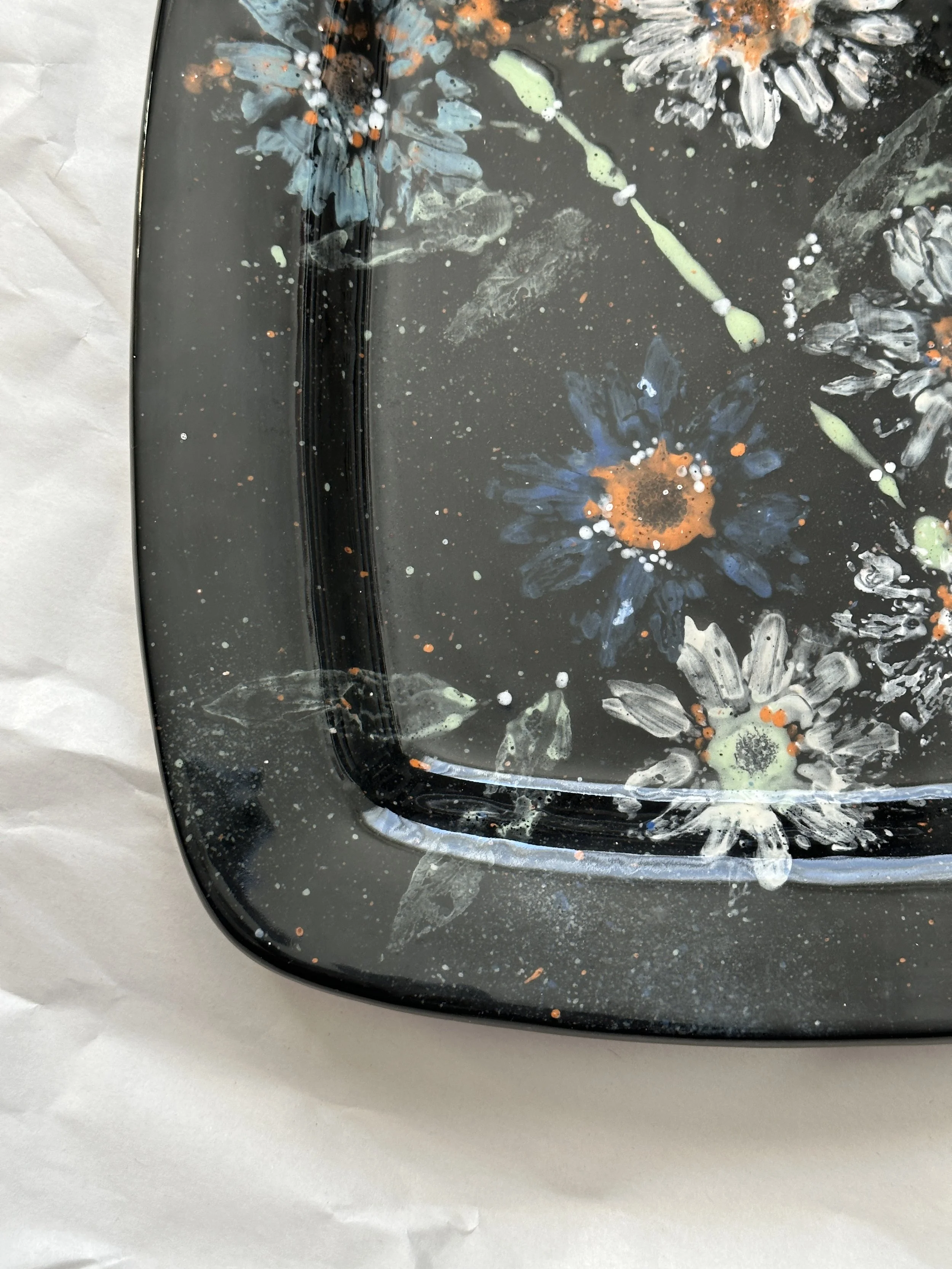  Square Rim Platter 12.25” x 12.25”  ShippingDaisy imprints in white, off white and a touch of blue, green and coral on black ground. Food safe, dishwasher safe, but best to hand wash. 