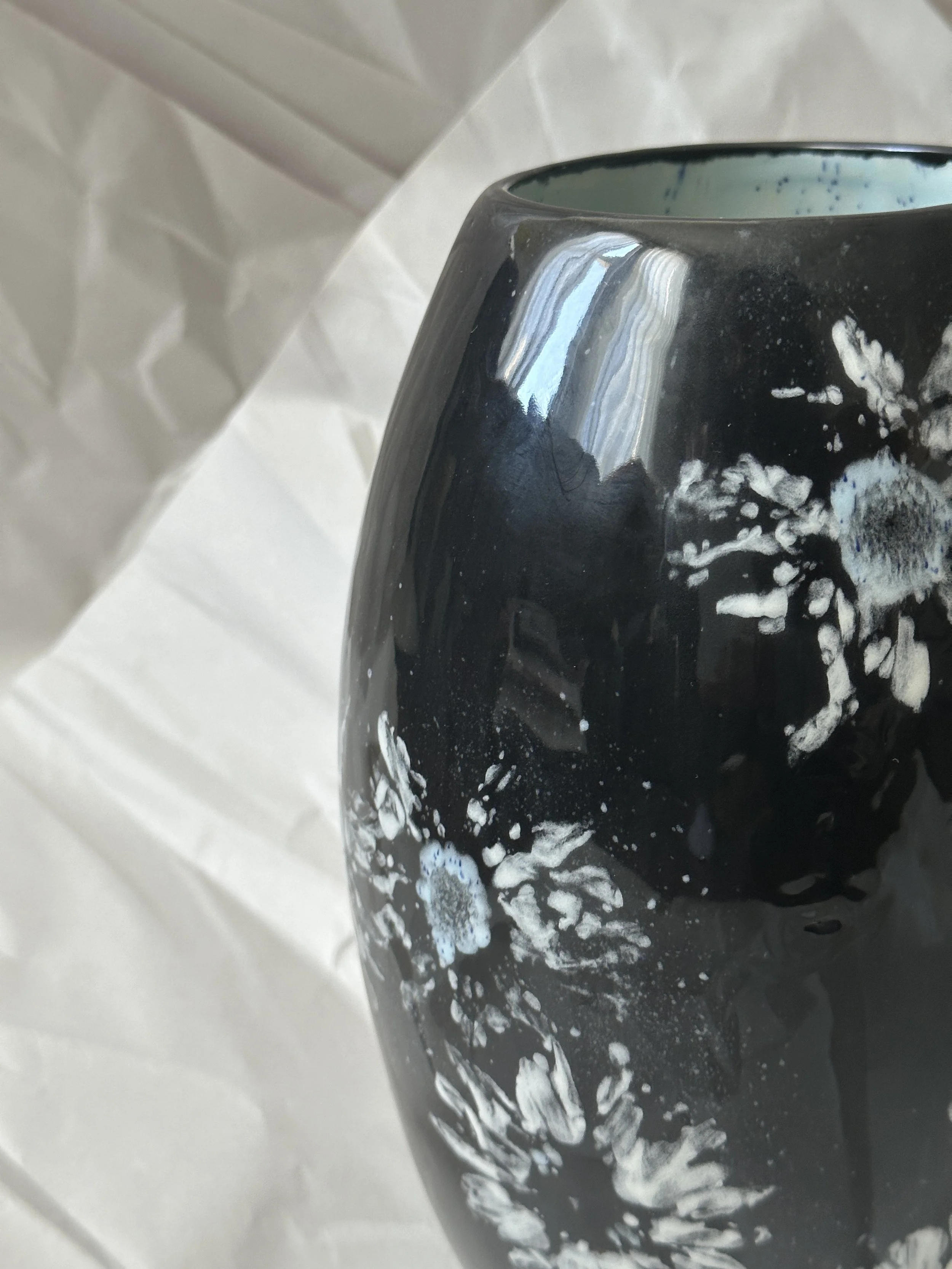  Tapered Vase 6.25” x 10” Daisy imprints in white, off white and a touch of blue on black ground. Blue inside.  Dishwasher safe, but best to hand wash. 