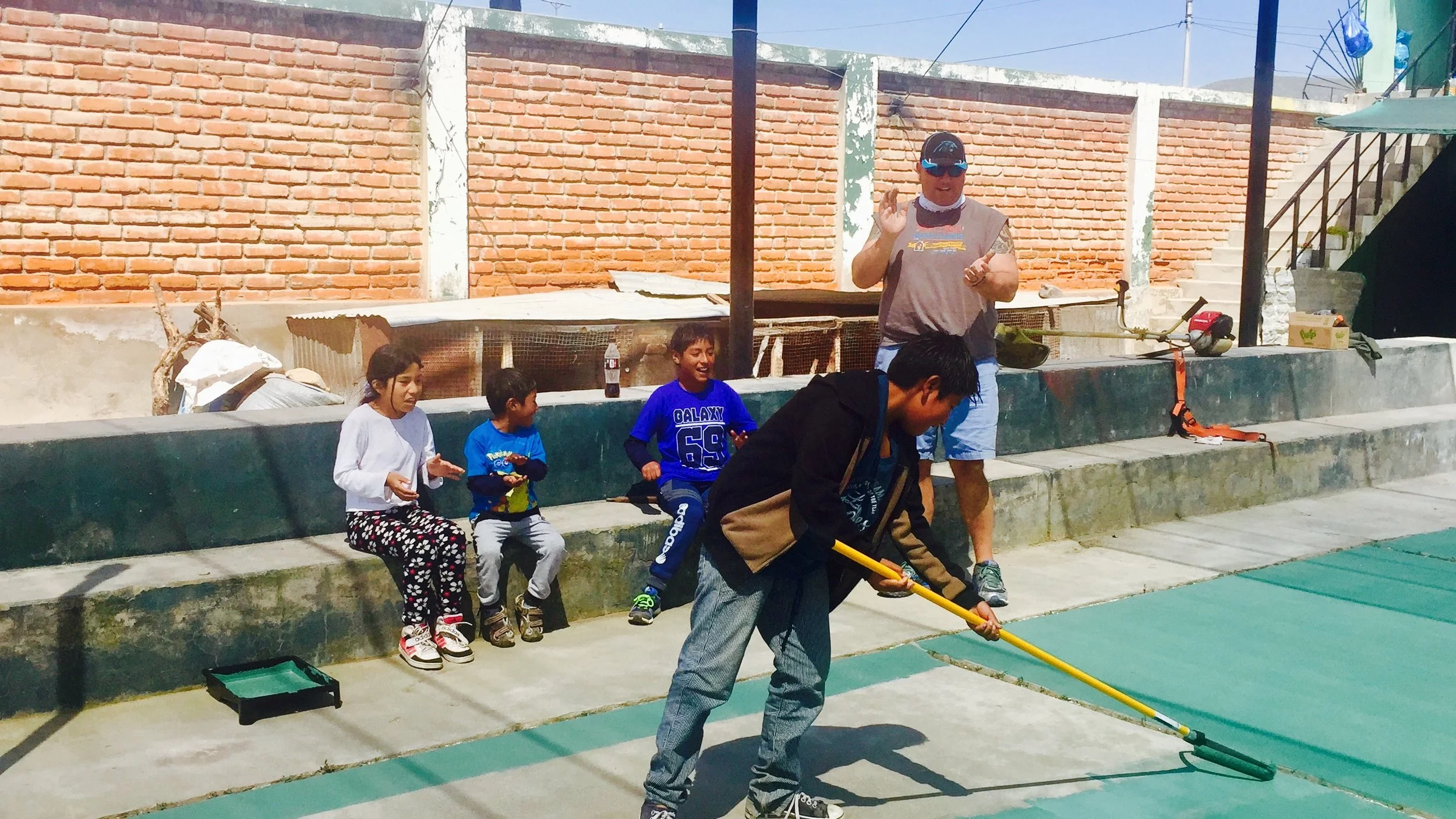 Volunteers and children painting the schoolyard in Cerrillo