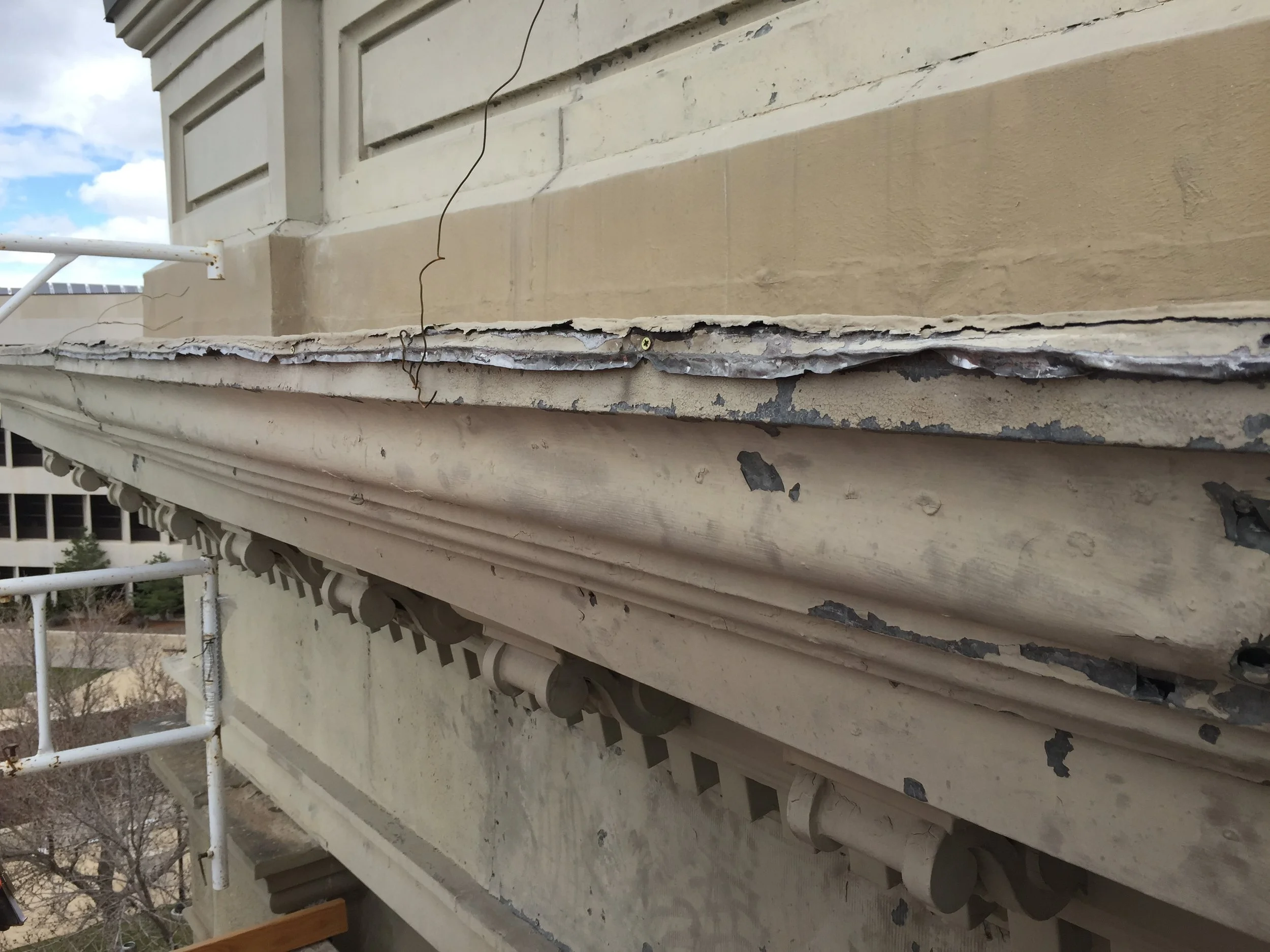  The damaged external entablature, made of sheet metal, is being replaced and a structurally sound steel system will secure it to the building. 