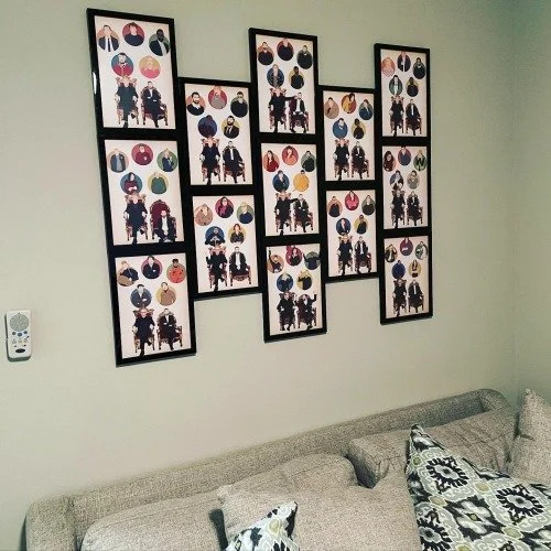Wall decor consisting of multiple framed collage photos, featuring silhouettes and colorful circular images, arranged above a gray sofa in a living room.