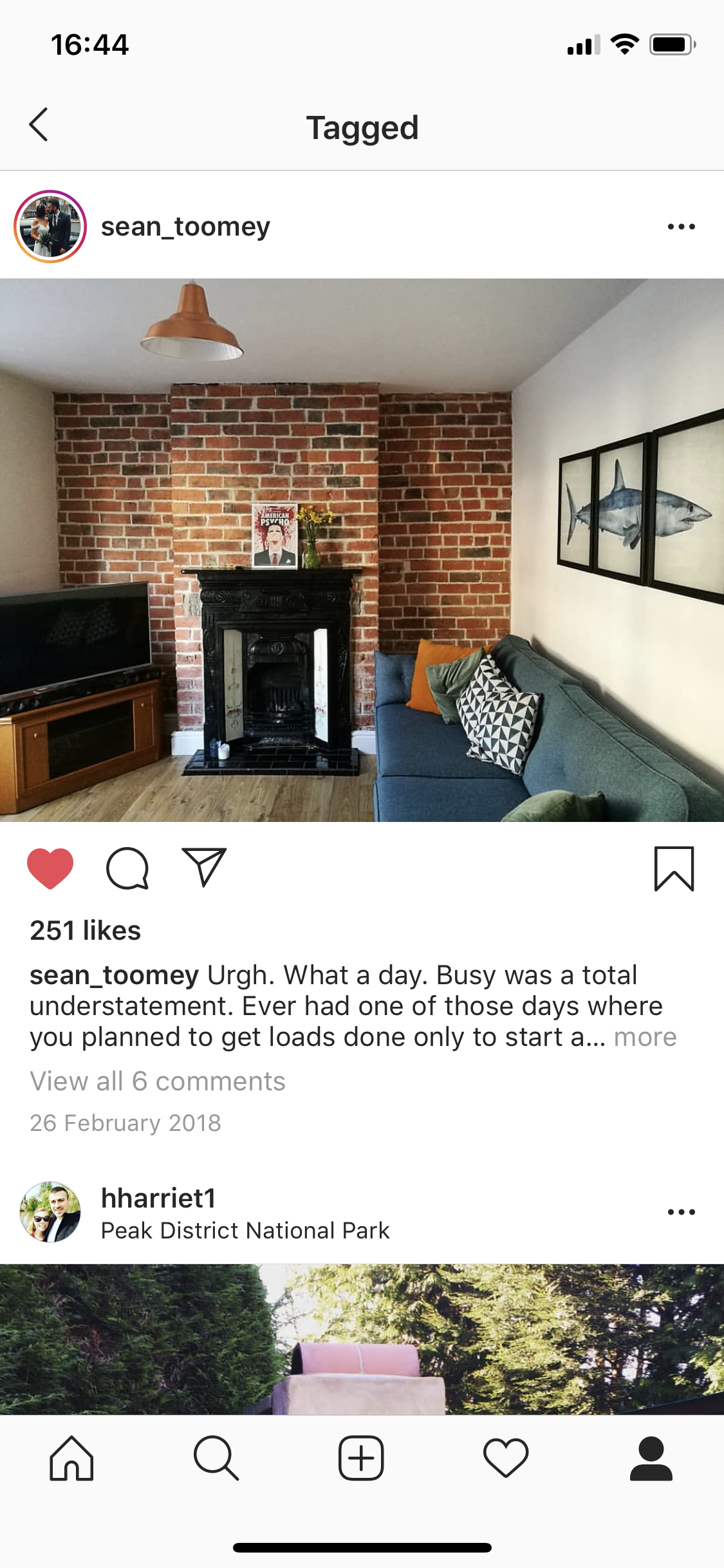 Living room with exposed brick wall, black fireplace, blue couch with pillows, wall art of a shark, and a TV on wooden stand.