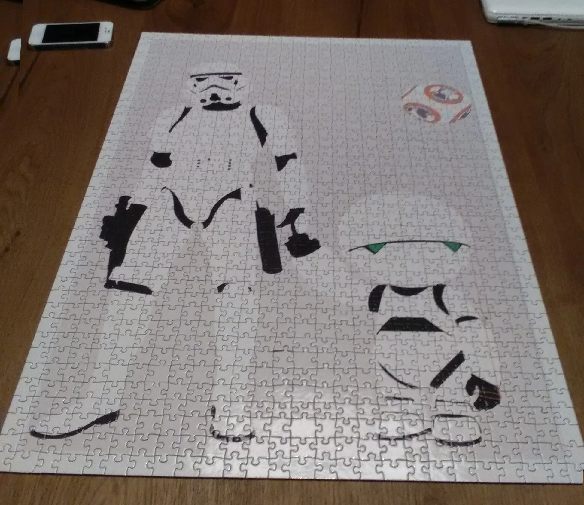 A partially completed jigsaw puzzle on a wooden table, depicting a black-and-white stormtrooper face from Star Wars, and some colorful puzzle pieces on the right side.