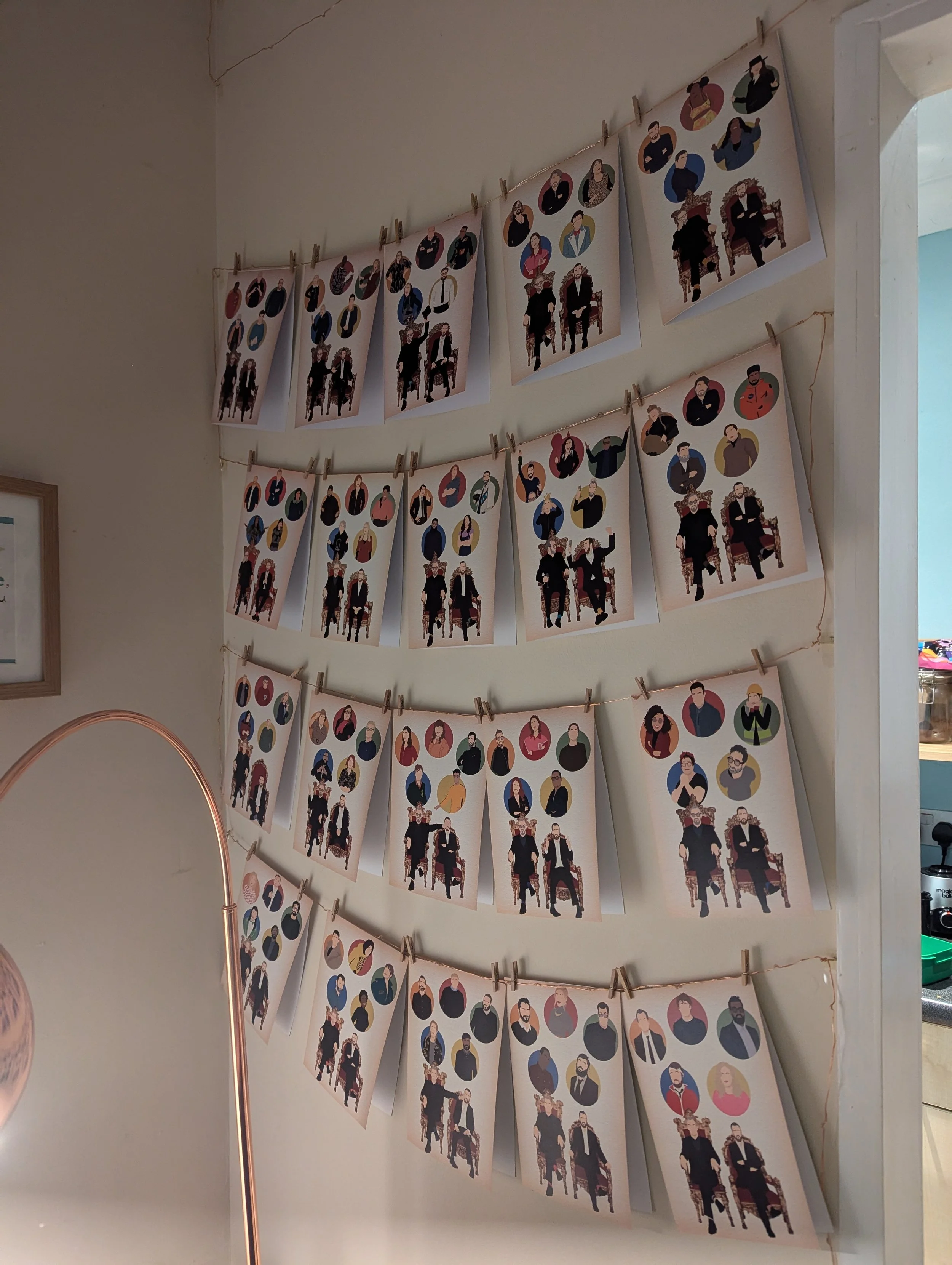 Illustrated portraits of various people hung on strings with clothespins on a wall, arranged in rows.