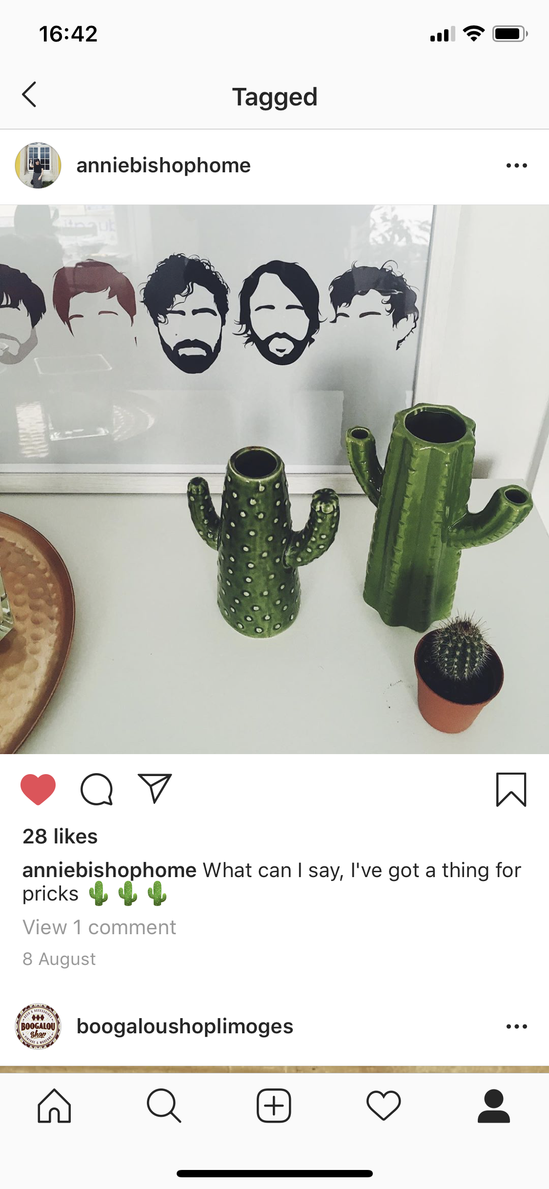 Two ceramic cactus-shaped vases and a small potted cactus on a white surface, with a framed portrait of five stylized faces in black and white.