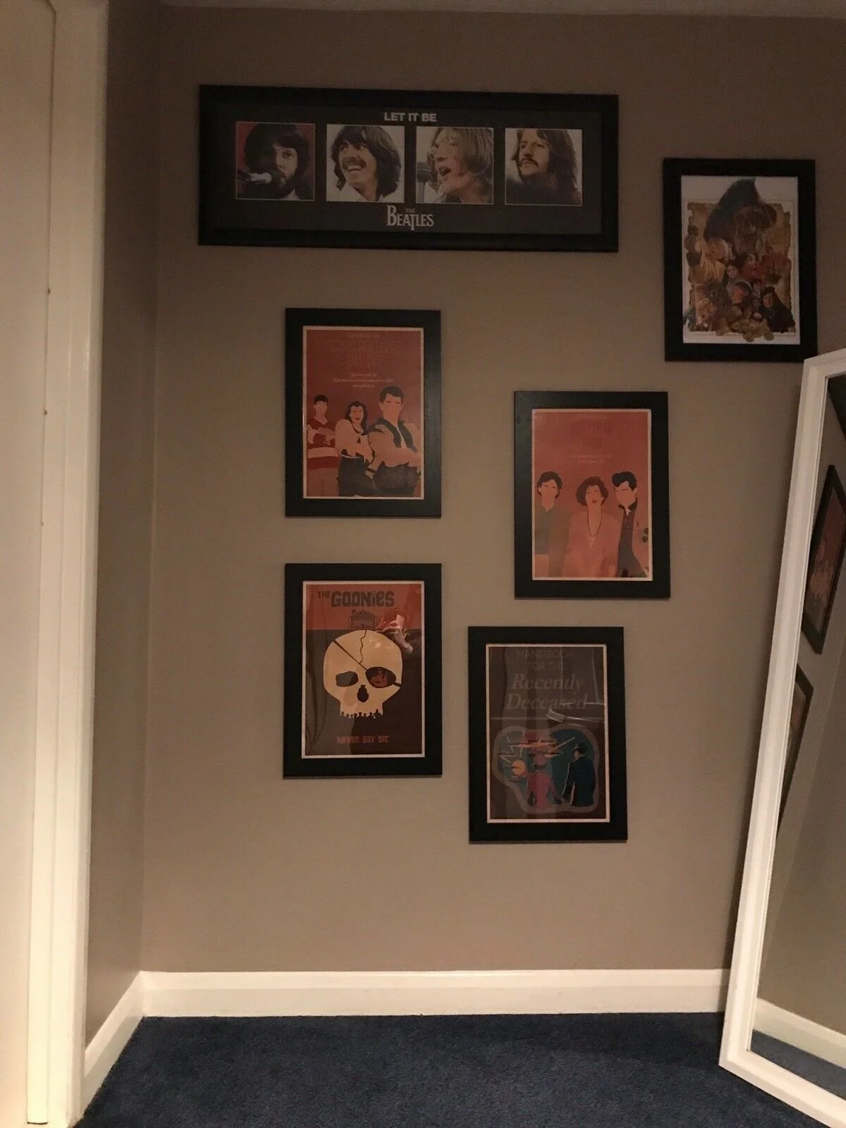 Wall decorated with framed posters and art, including The Beatles, The Goonies, and other artwork, in a cozy interior space.