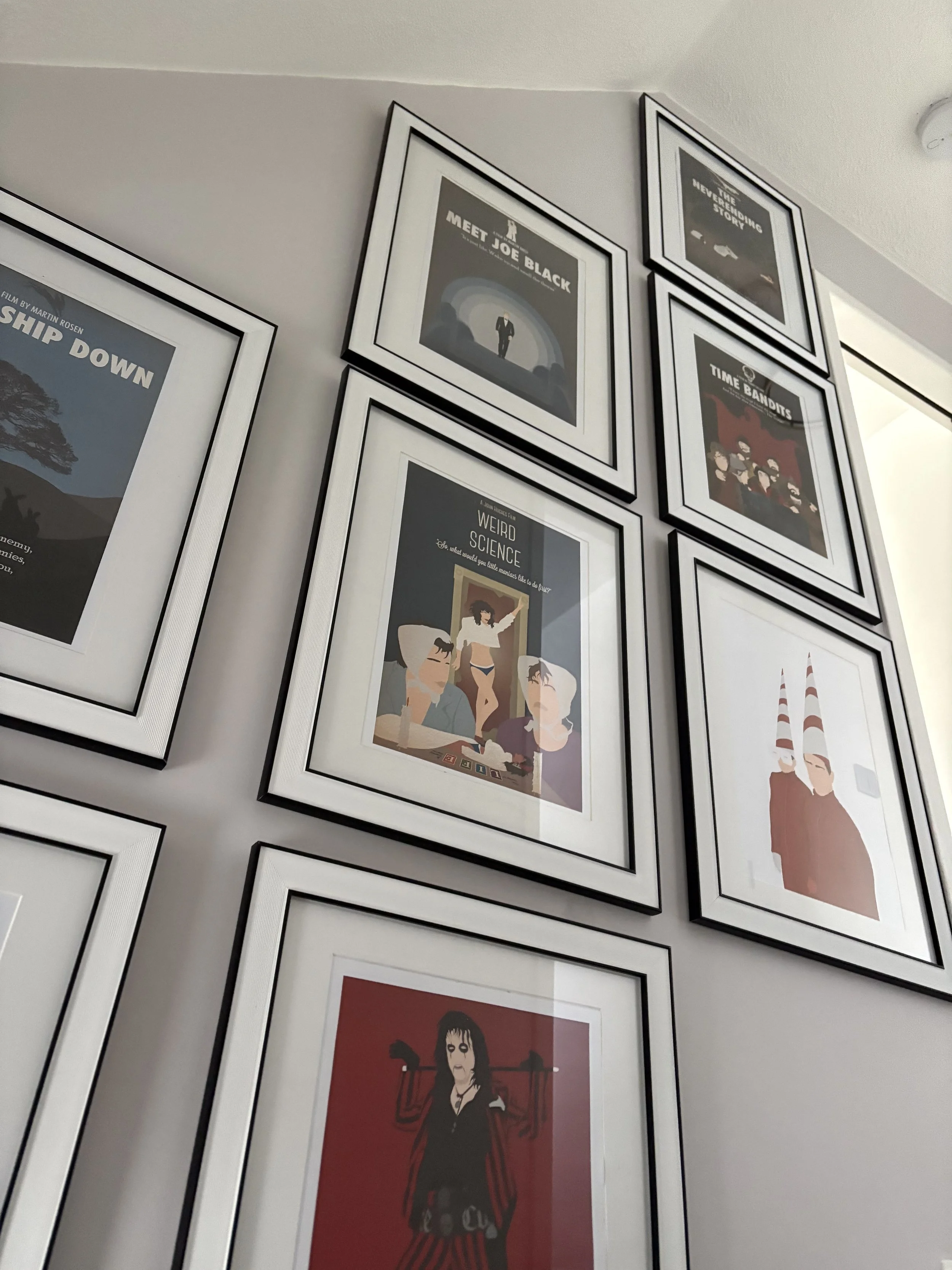Gallery wall with framed movie posters featuring characters and artistic designs.