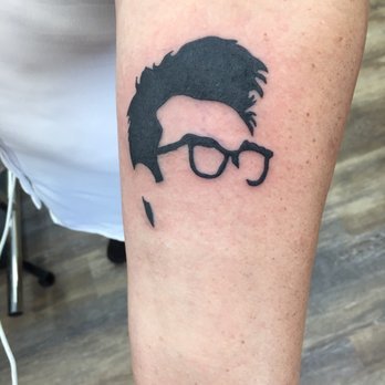 Tattoo of a person's hairstyle and glasses on a person's arm.