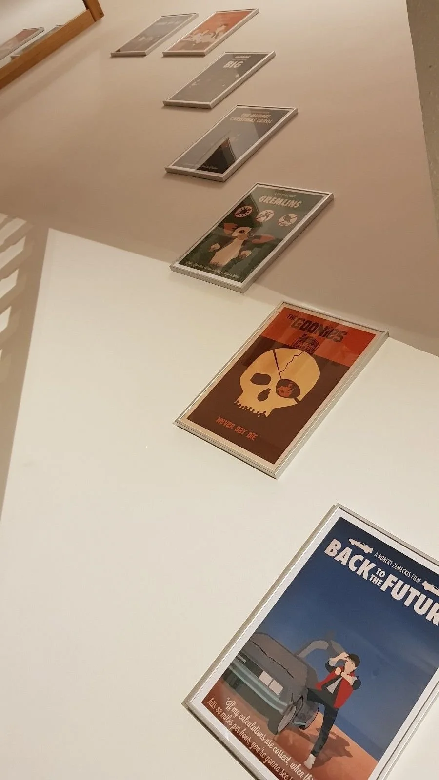 Display of vintage movie posters on a white table, including 'Back to the Future,' 'The Goonies,' 'Gremlins,' and other classic films.