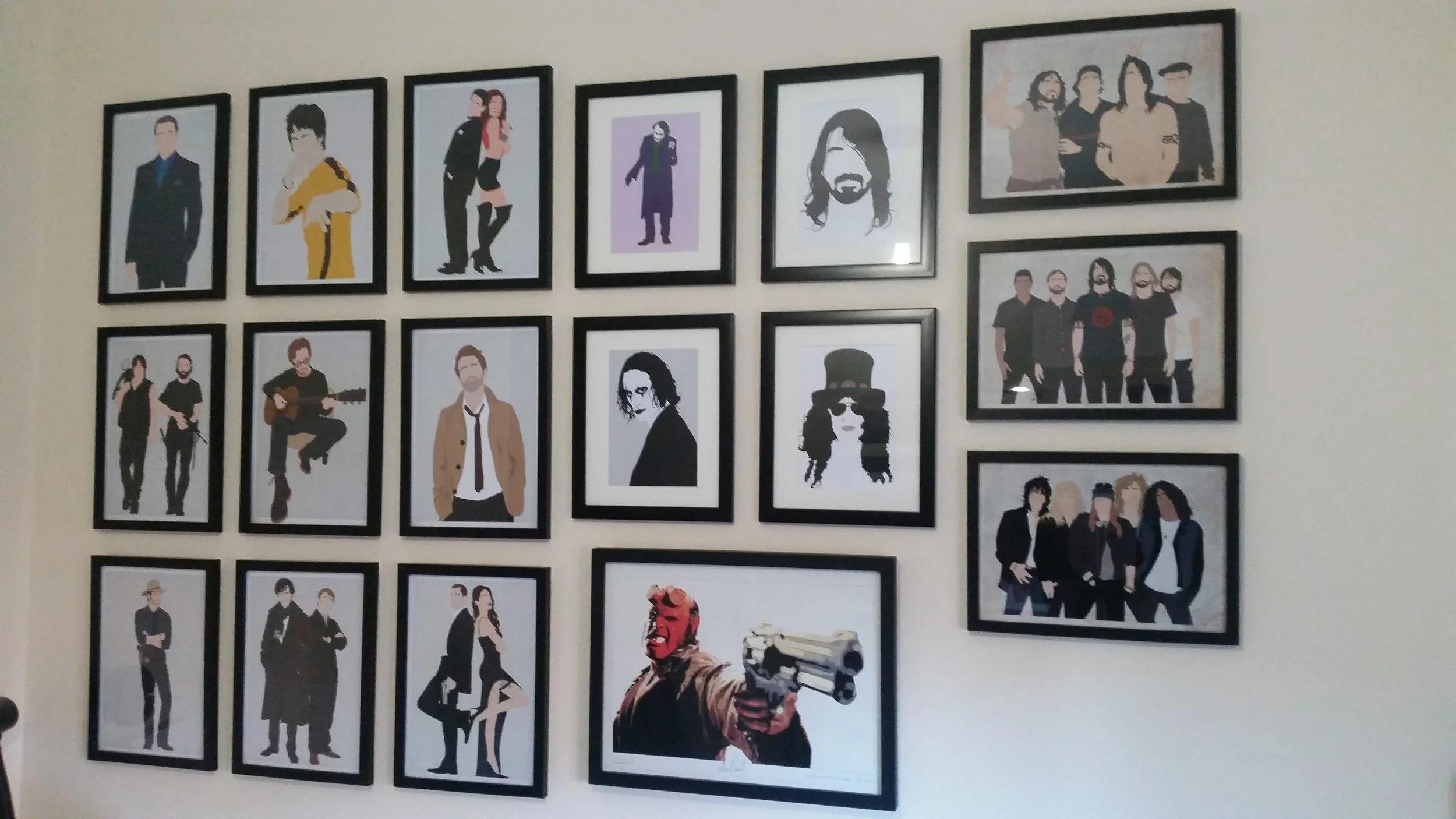 Collection of framed pop art-style portraits of musicians and bands on a wall.