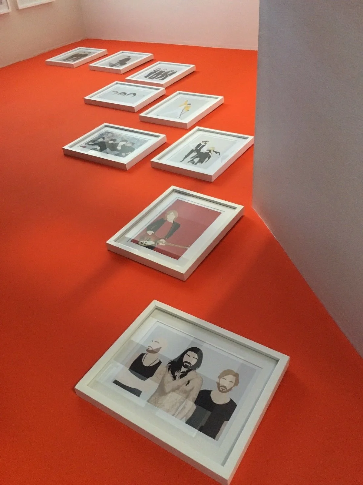 A series of framed illustrations arranged on an orange surface. The illustrations depict various cartoon-style characters and scenes.