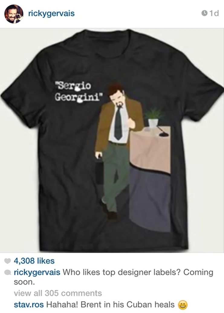 Black T-shirt with cartoon illustration of a man in a brown blazer, tie, and green pants, standing next to a desk with a potted plant and a microphone. The shirt has the text "sergio Georgant" on it.