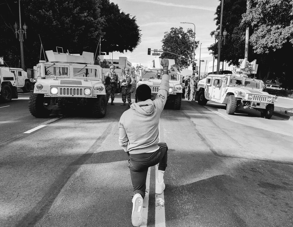  A man kneels before National Guard Troops called in to Los Angeles, CA due to the massive uprising after the killing of George Floyd in Minneapolis, MN. June 2020.  Los Angeles, CA. 